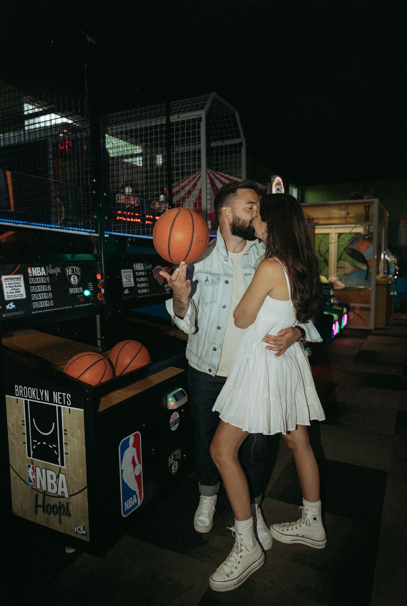 NBA-themed arcade basketball game being played in a dark entertainment space.