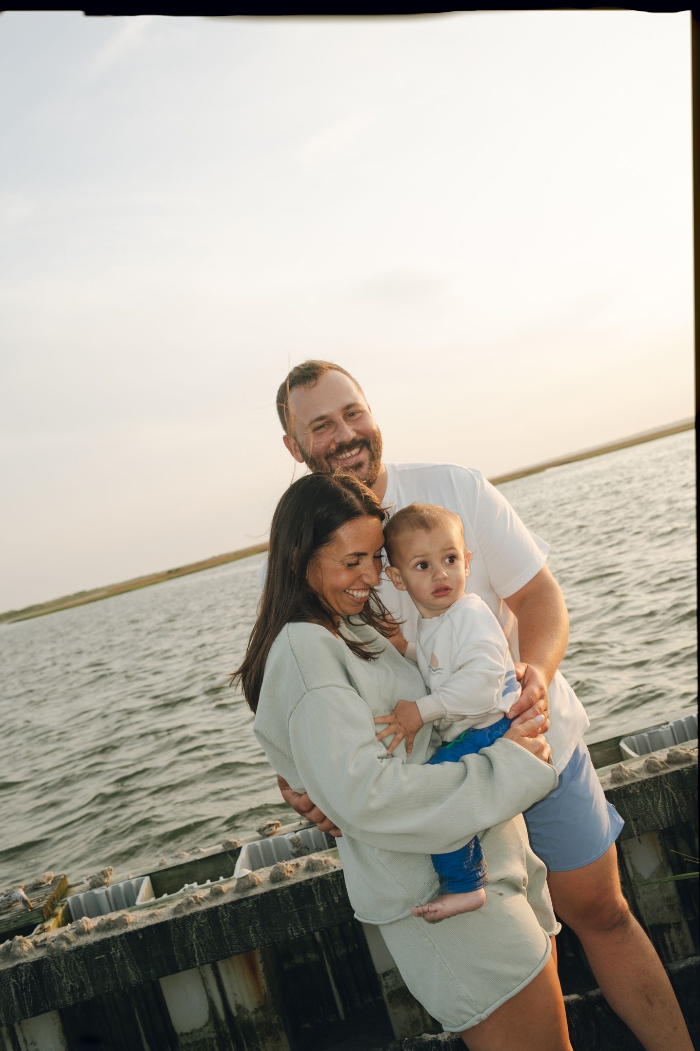 Family shares joyful moment together on wooden pier at sunset.