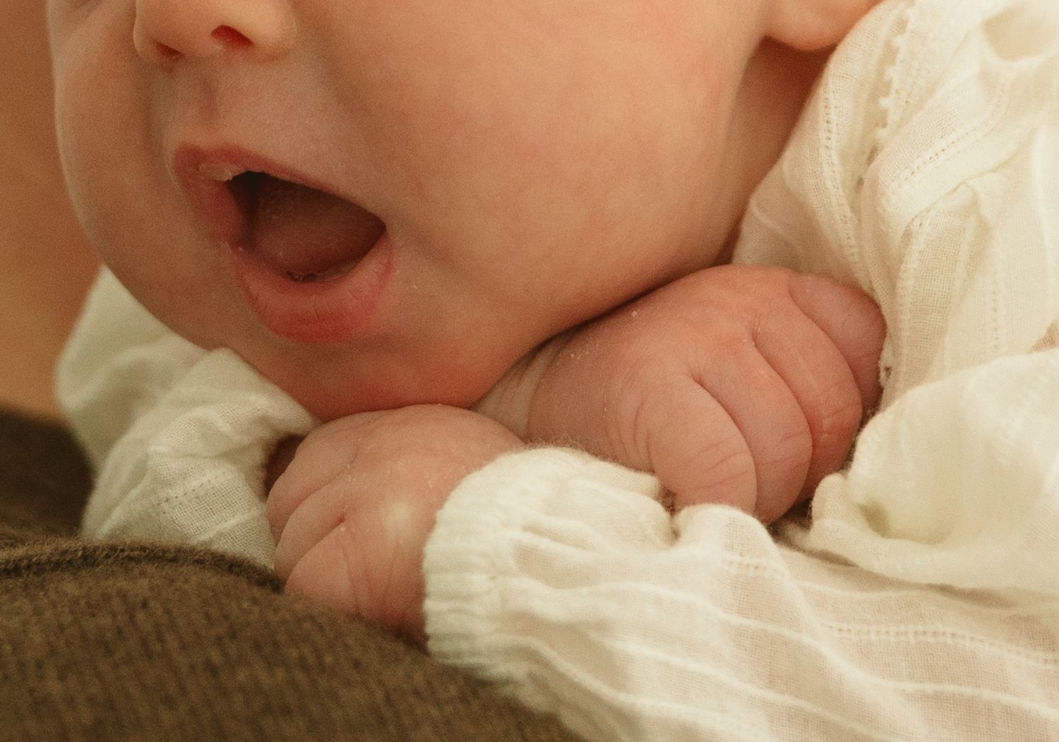 Close-up details of soft infant features against white fabric.