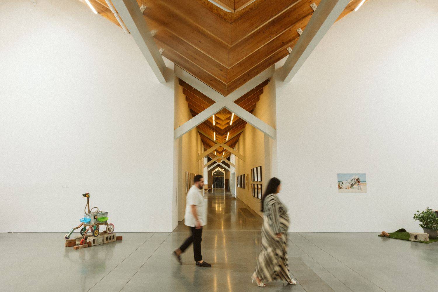 Minimalist art gallery interior with wooden ceiling beams and white walls.