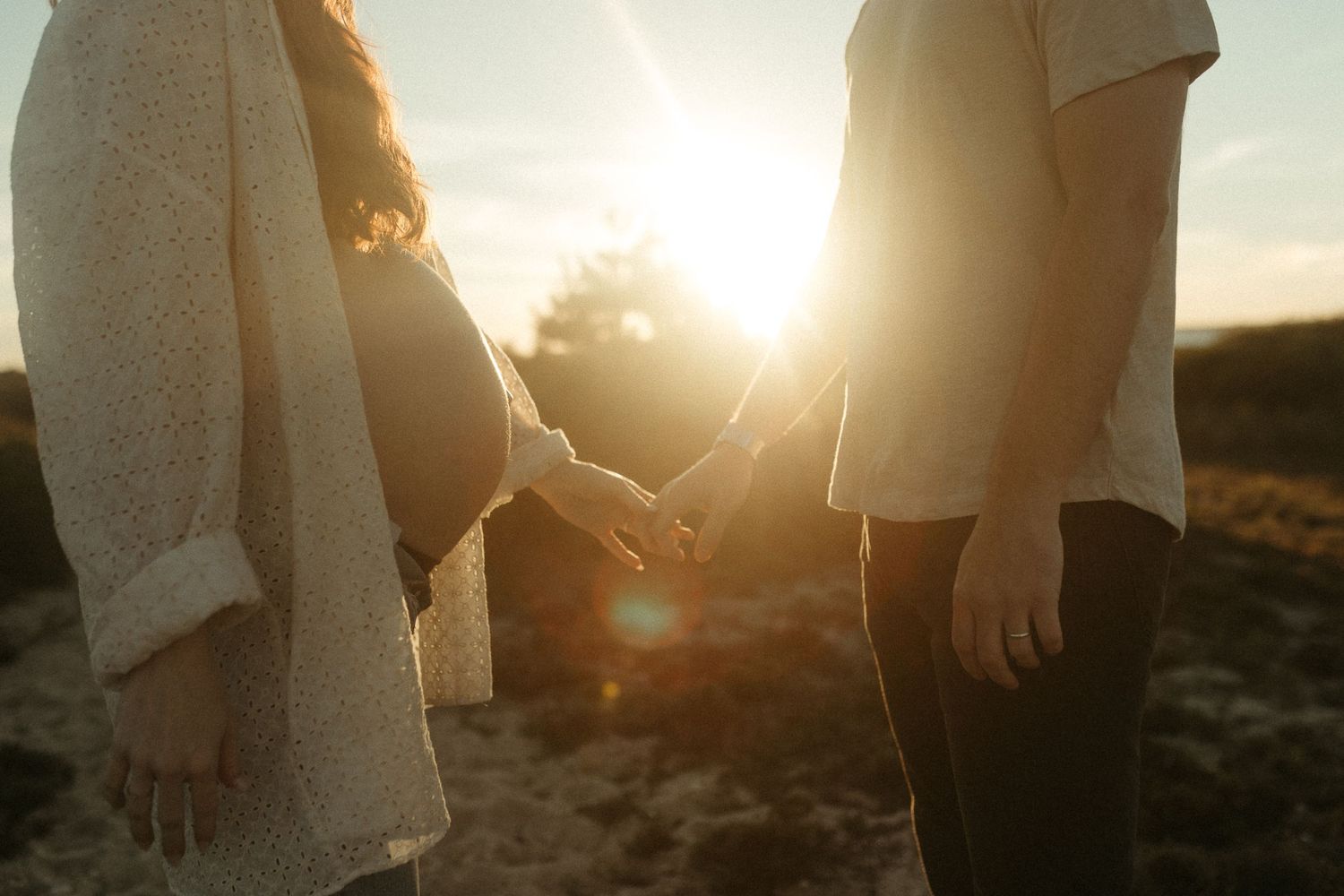 Silhouettes of people embracing against a golden sunset backdrop.
