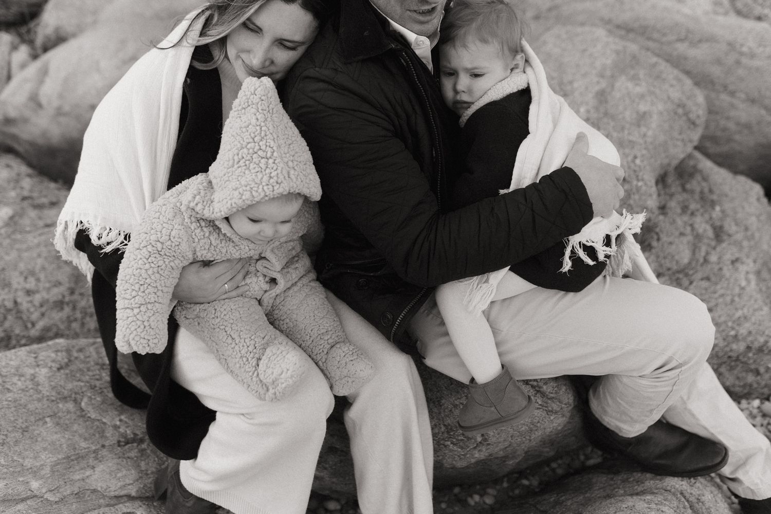 Playful sequence of people lying on rocks having fun together in black and white.