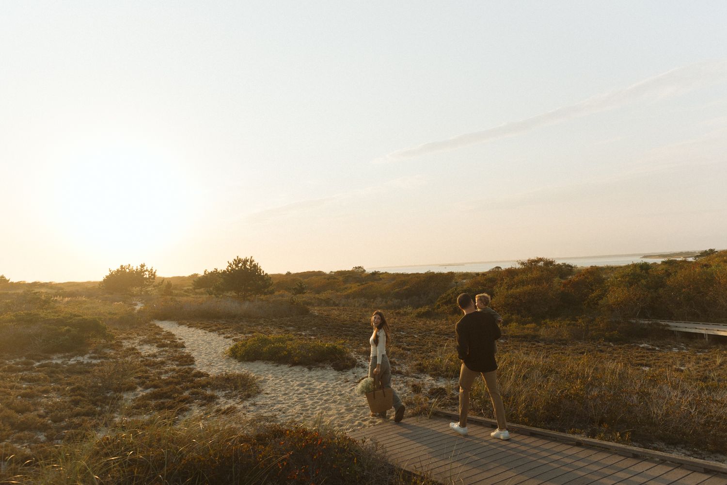 A couple walking along a scenic coastal path at sunset.