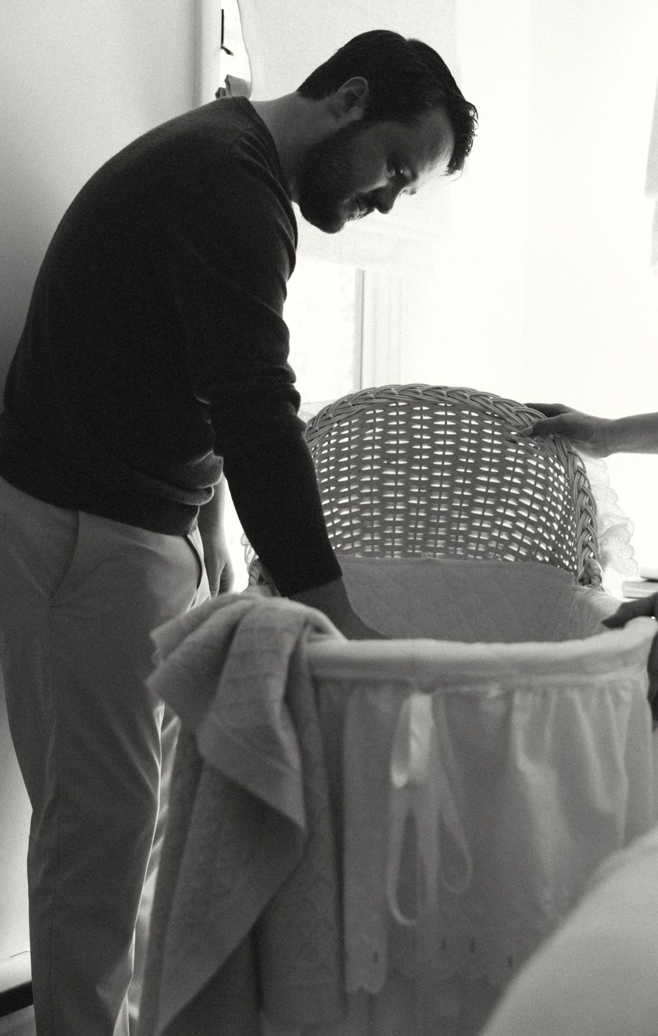 Black and white image of someone arranging white linens on furniture.