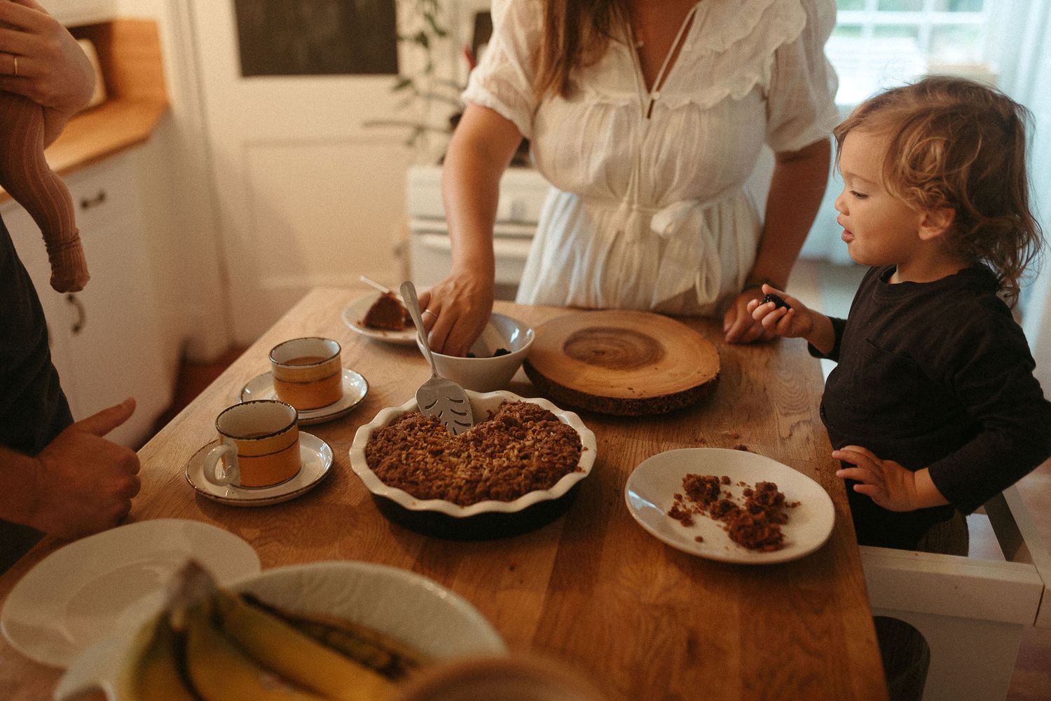 Sunlit dining scene with plates of food and beverages on a rustic wooden table.