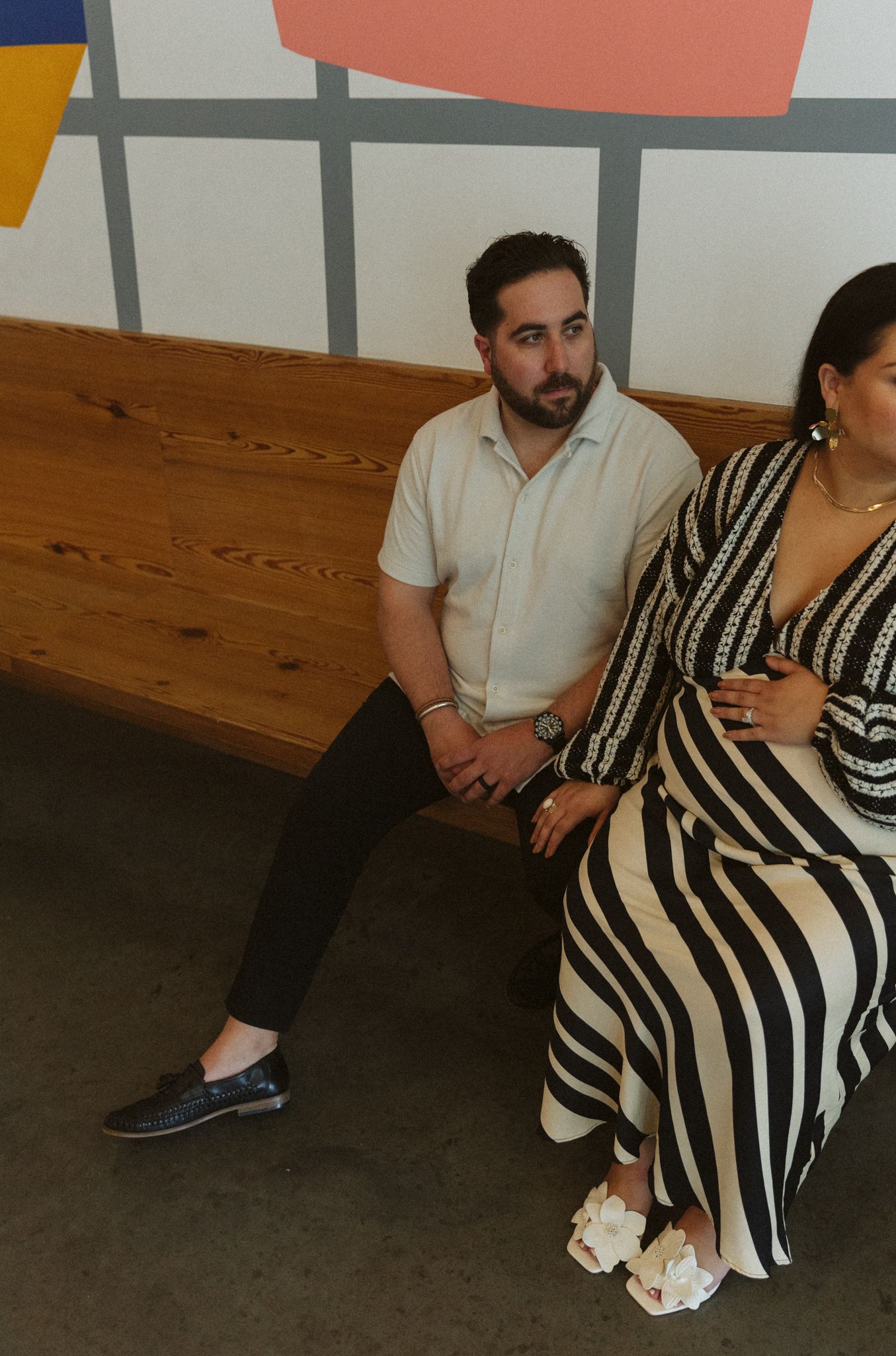 People sitting on a wooden bench wearing black and white striped clothing.