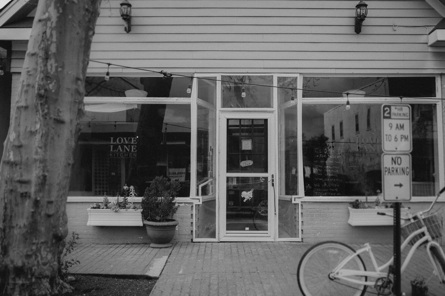 White clapboard building exterior with windows and light fixtures in black and white.