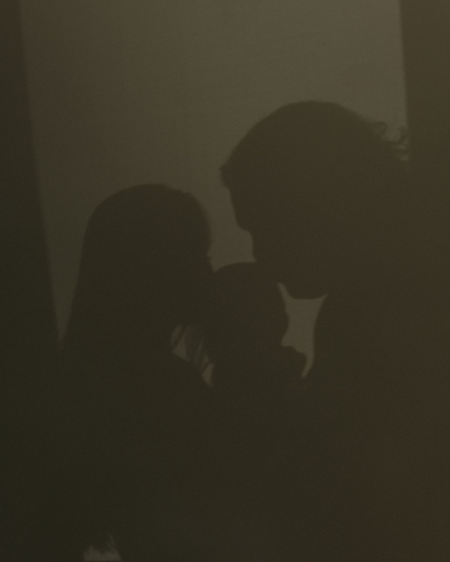 Dramatic silhouette of two people facing each other in dim, moody lighting creating an intimate and mysterious atmosphere.