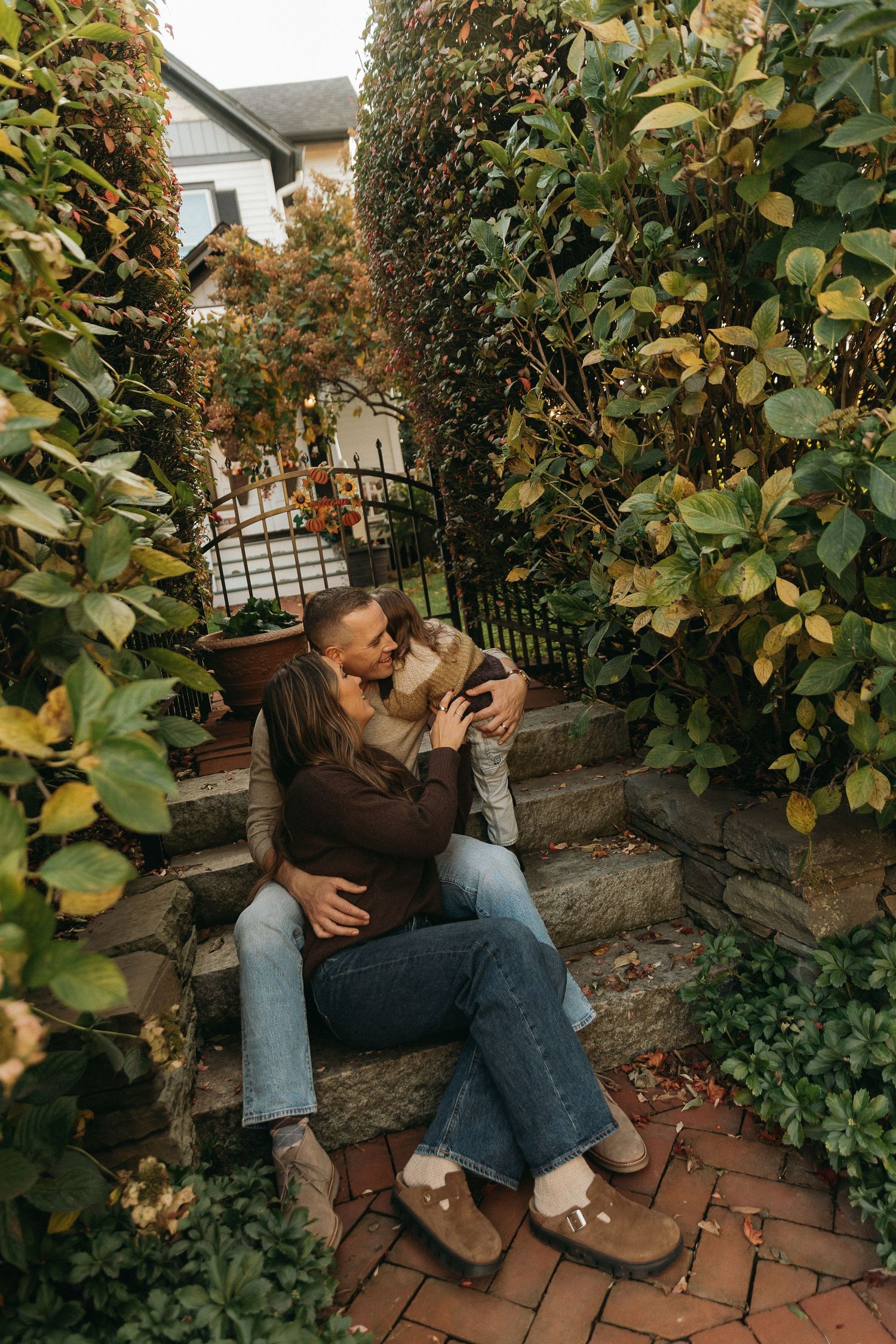 Couple sitting on brick steps surrounded by autumn foliage.