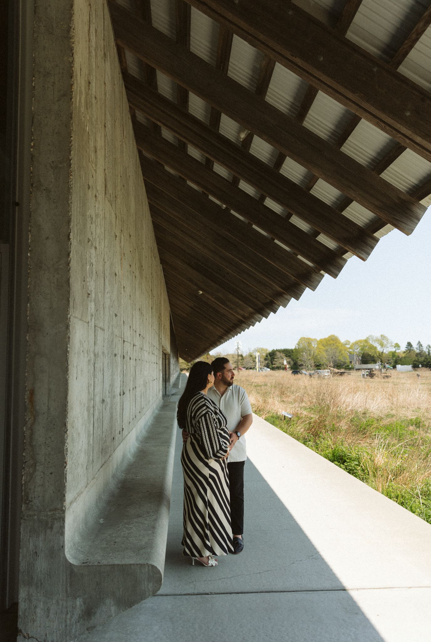 Concrete architectural structure with angled roof overlooking grassy field.
