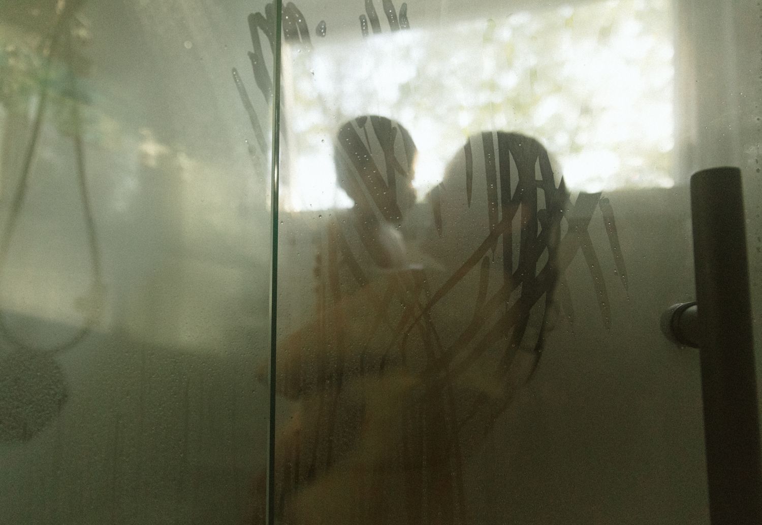 Steamy glass shower door with water droplets creating a foggy effect.