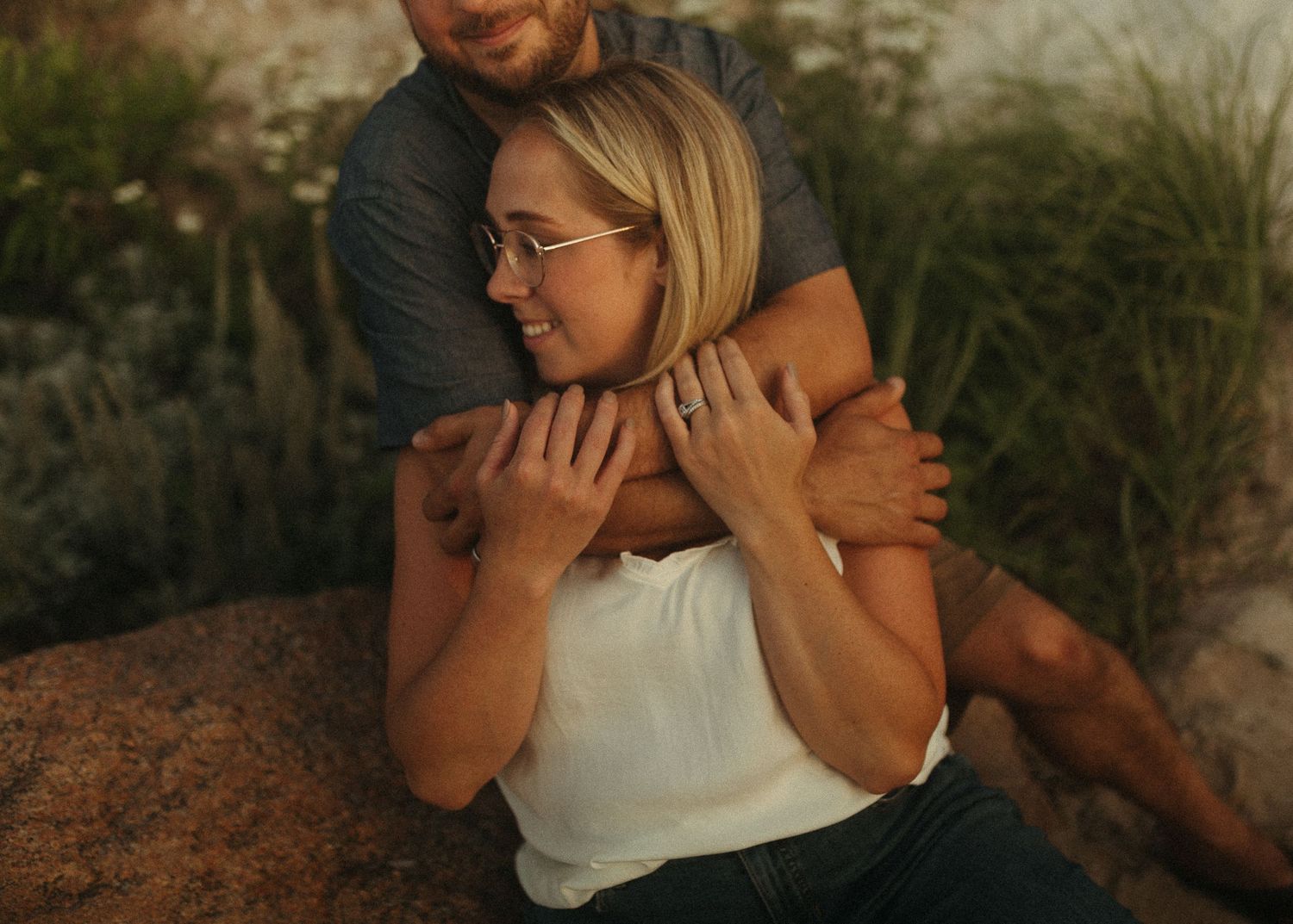 Couple sharing intimate moment on coastal cliffside at sunset.