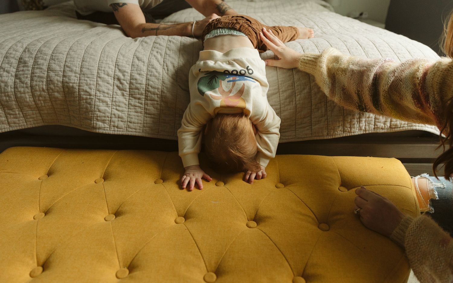 A playful moment captured on a yellow tufted ottoman.