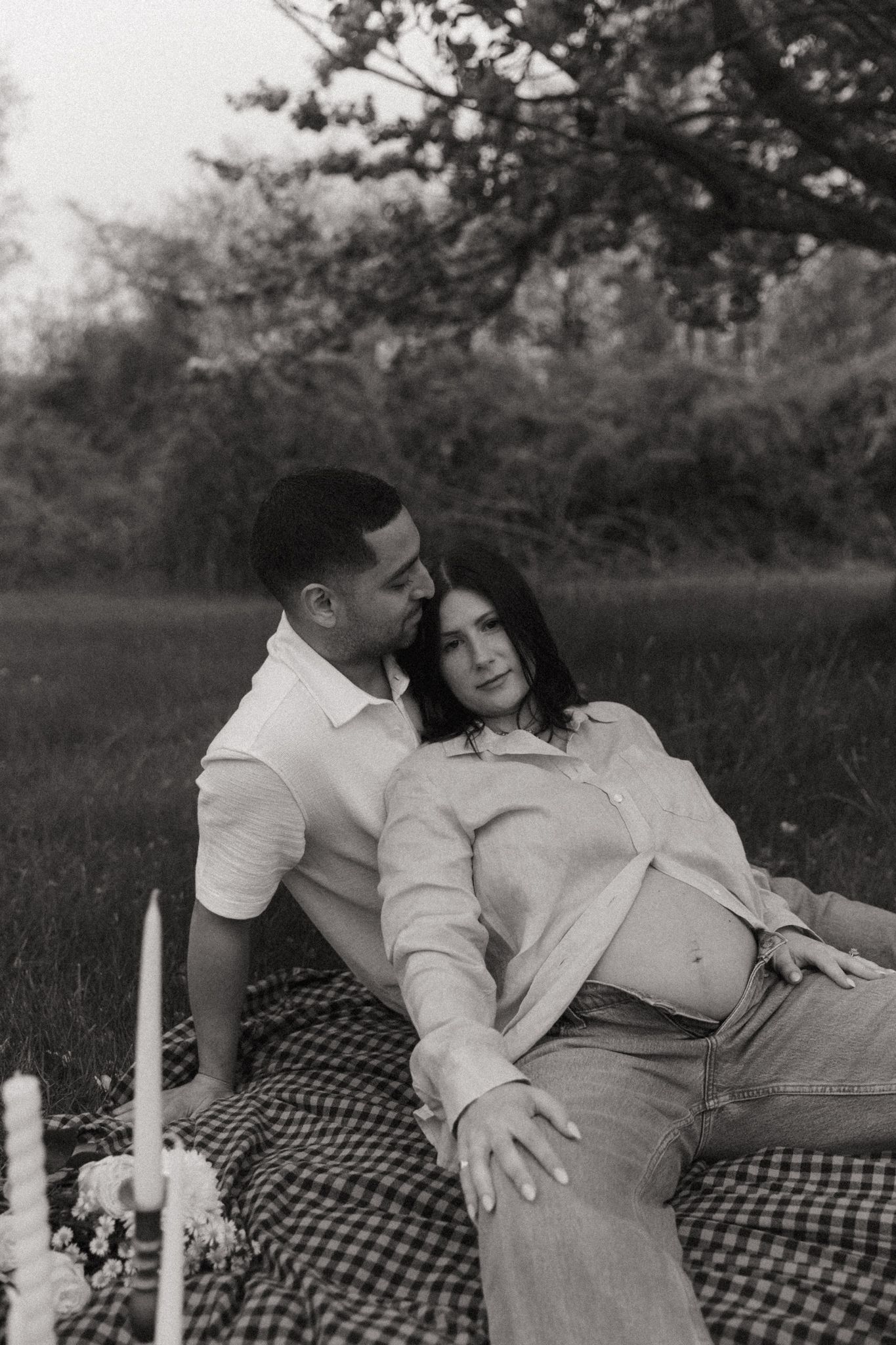 An intimate black and white portrait of a couple relaxing on a picnic blanket.