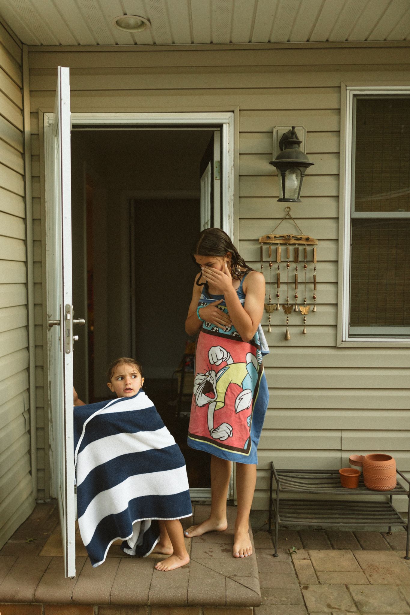 A sequence showing someone drying off with a black and white striped towel on a porch.