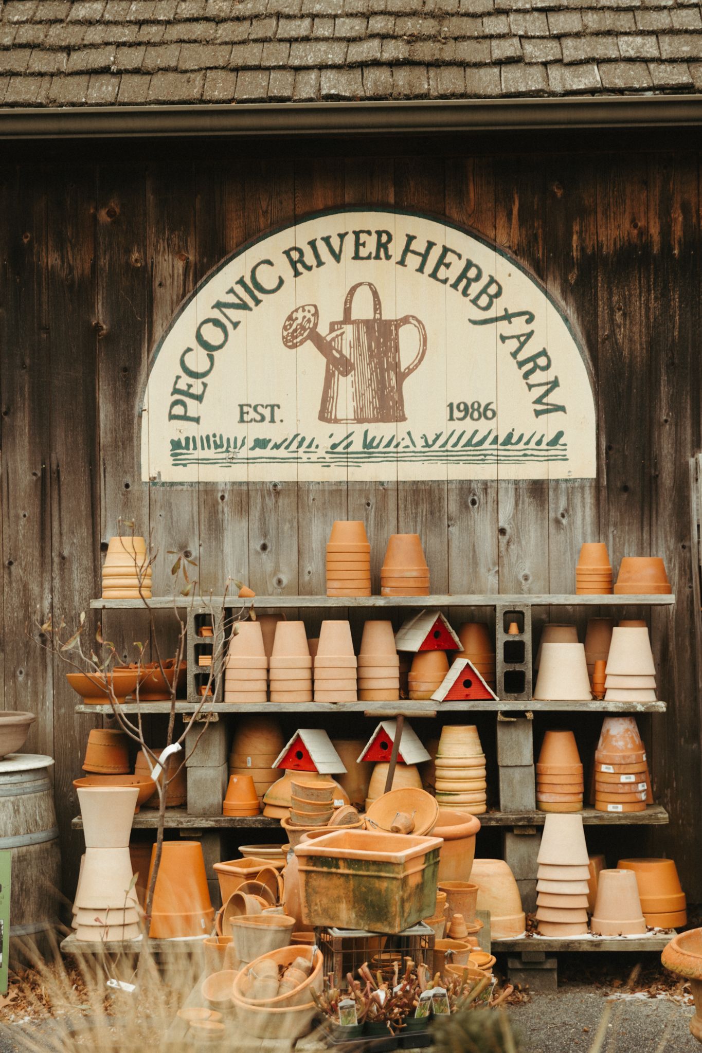Rustic garden shop display with terracotta pots and wooden signage.