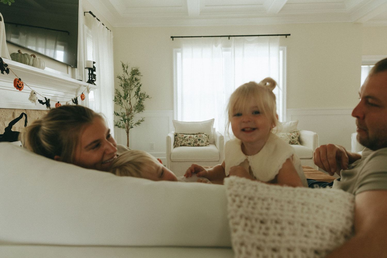 Happy family with a smiling toddler enjoying a cozy moment together in a bright living room.