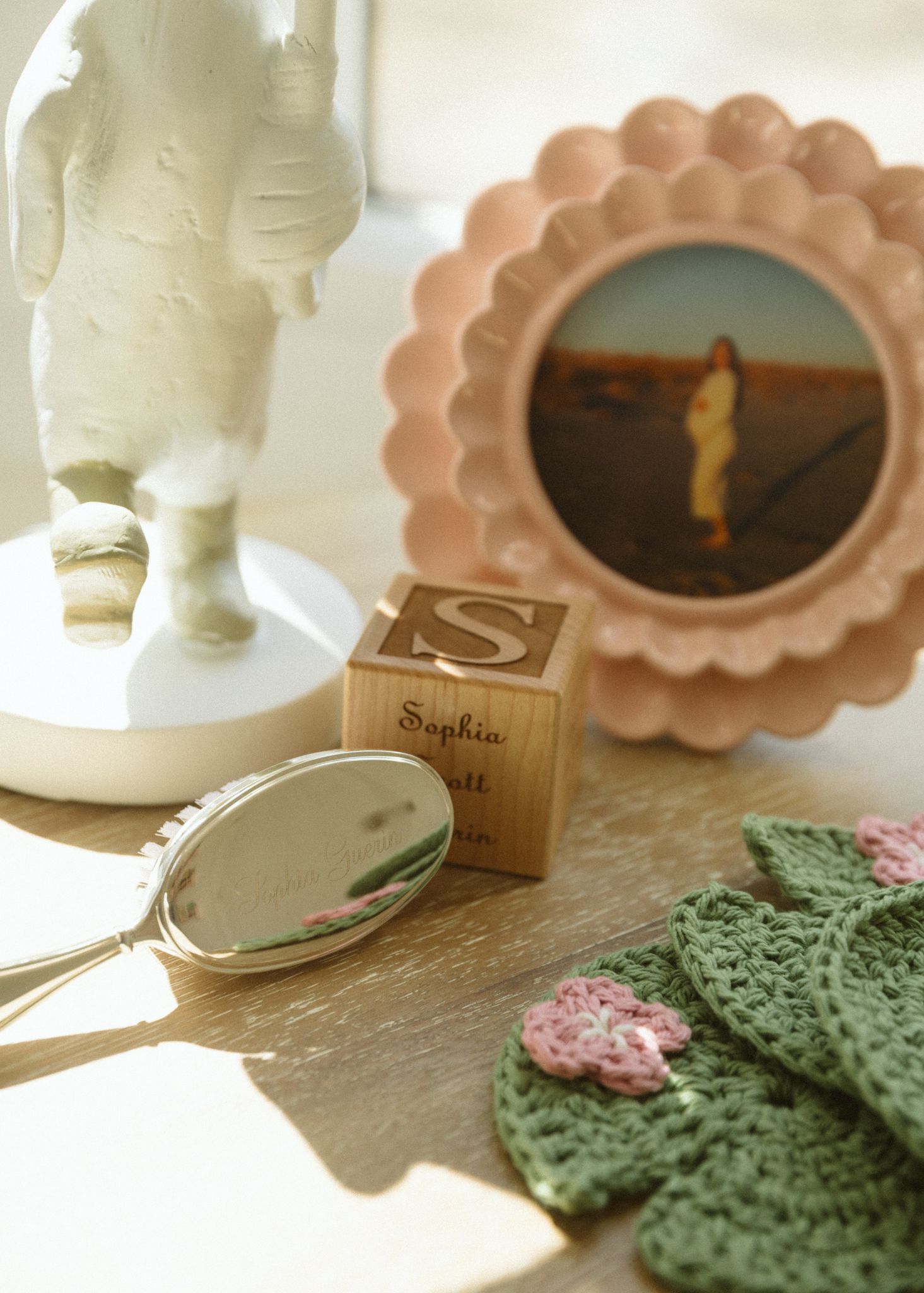 Vintage-style pink scalloped mirror and green knit items in soft sunlight.