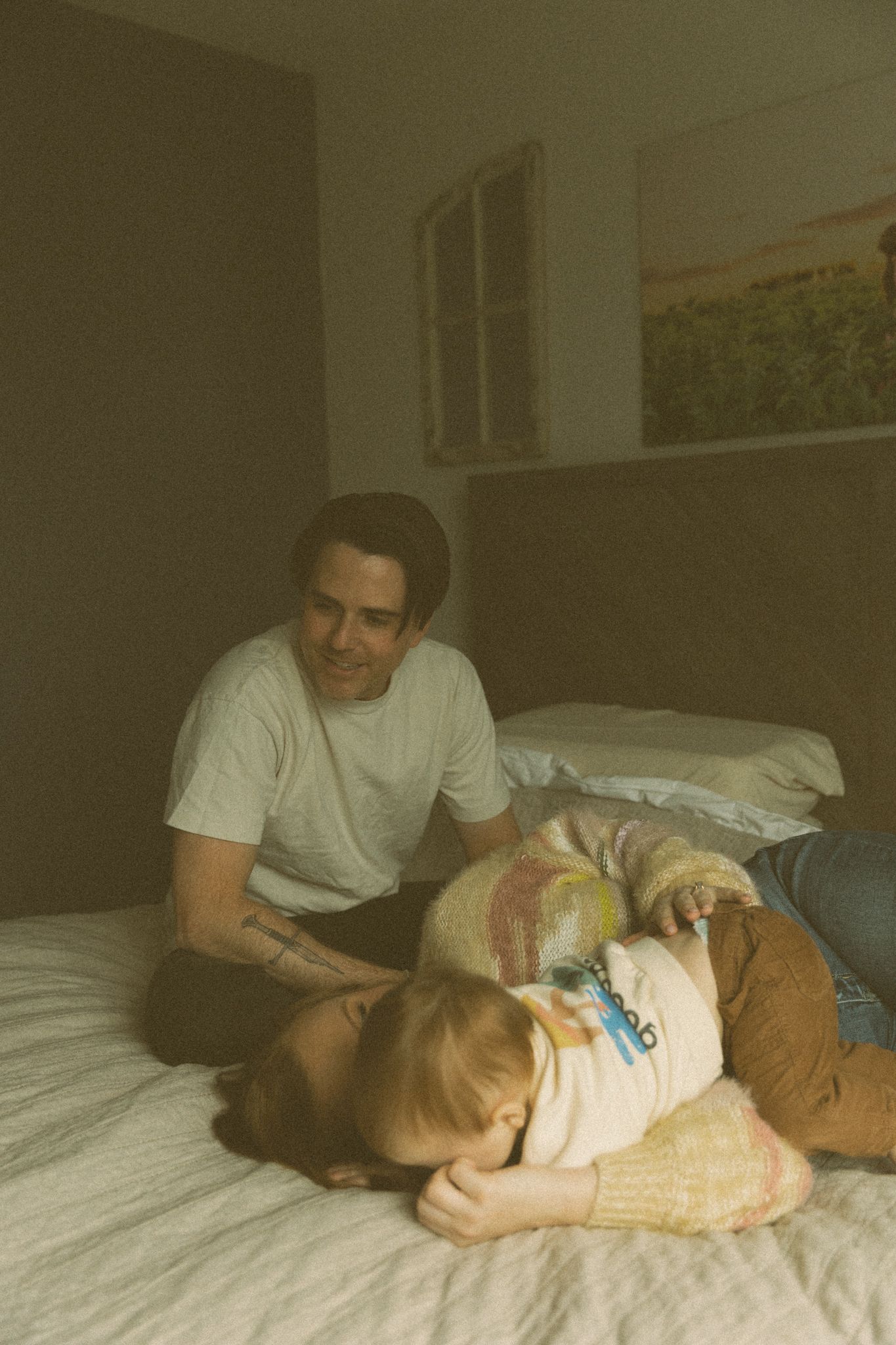 A warm and intimate moment captured on a bed with soft lighting and vintage tones.