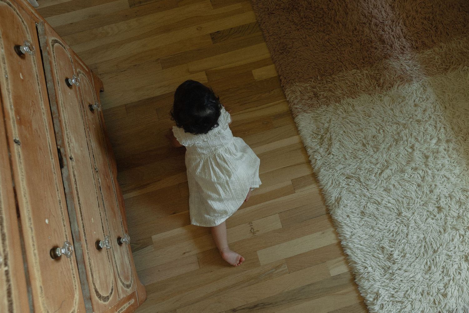 A low-angle view of a wooden floor and textured wall in natural light.