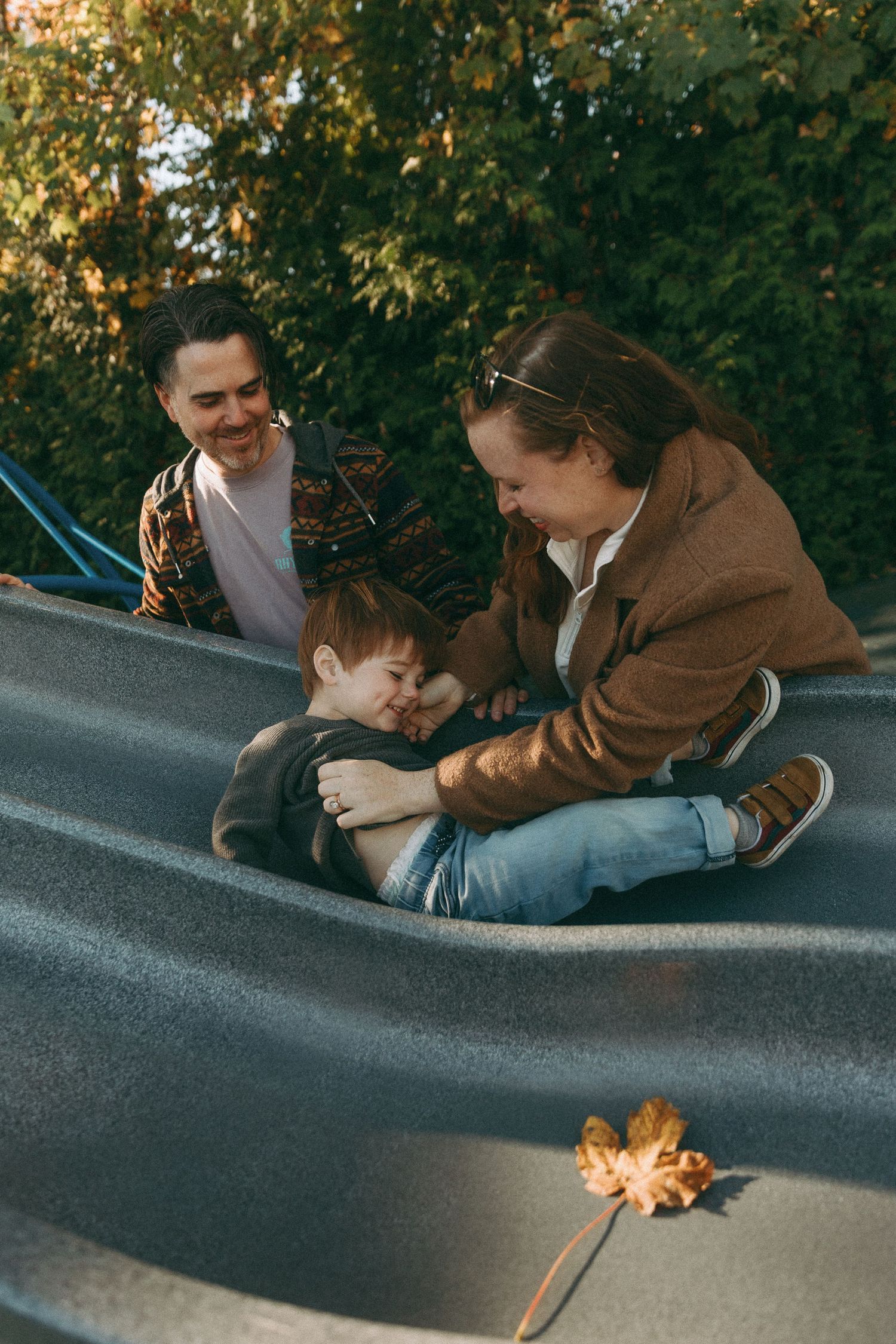 People interacting with a small fire on a curved surface outdoors during autumn.