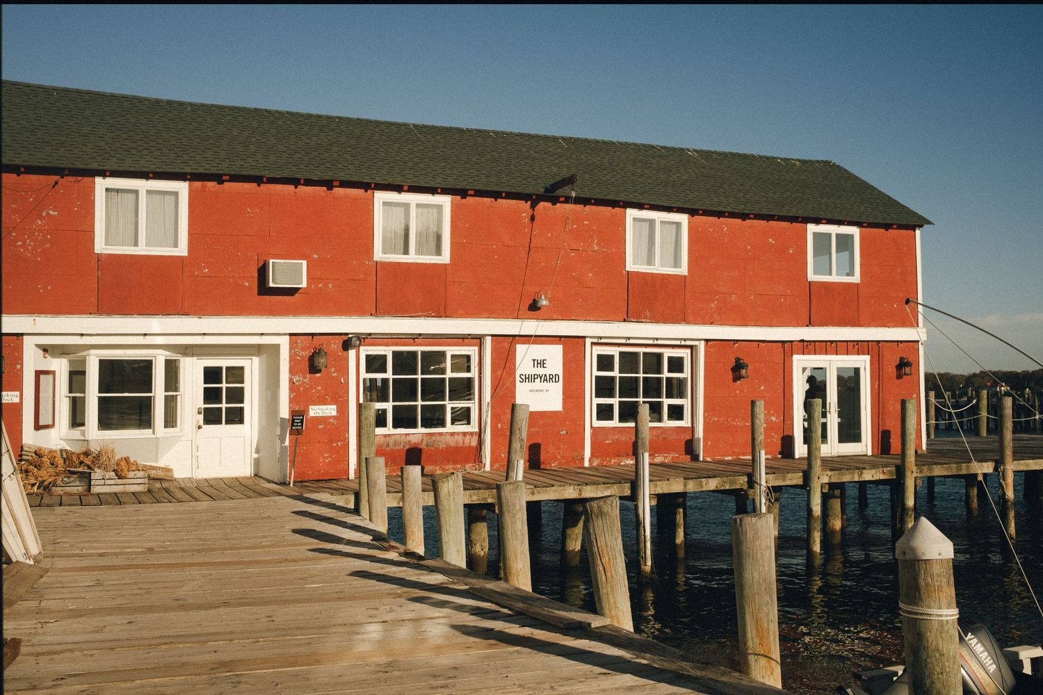 Red waterfront building with white trim and wooden dock posts.