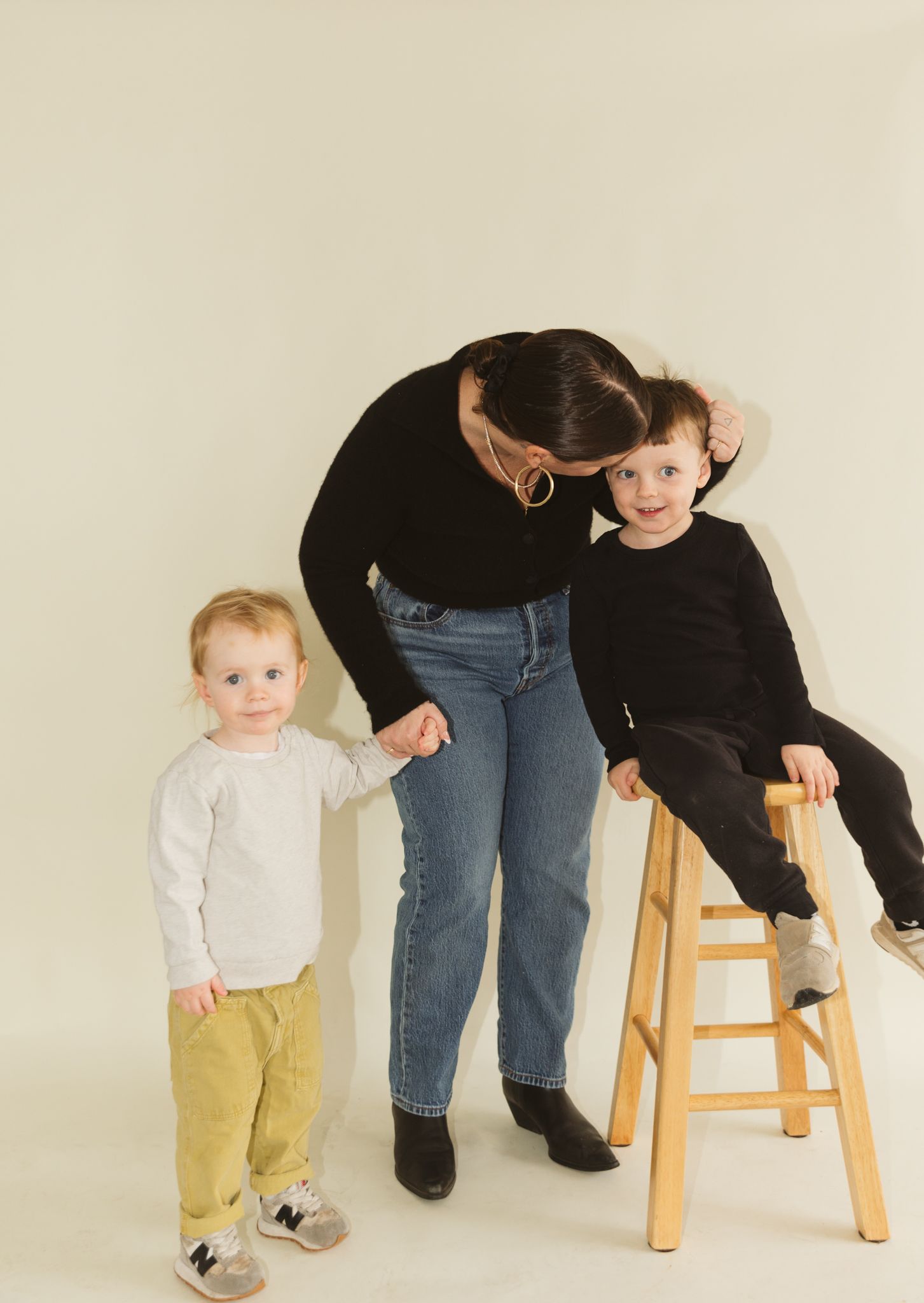 Studio photos showing interactions between people near a wooden stool against a white backdrop.