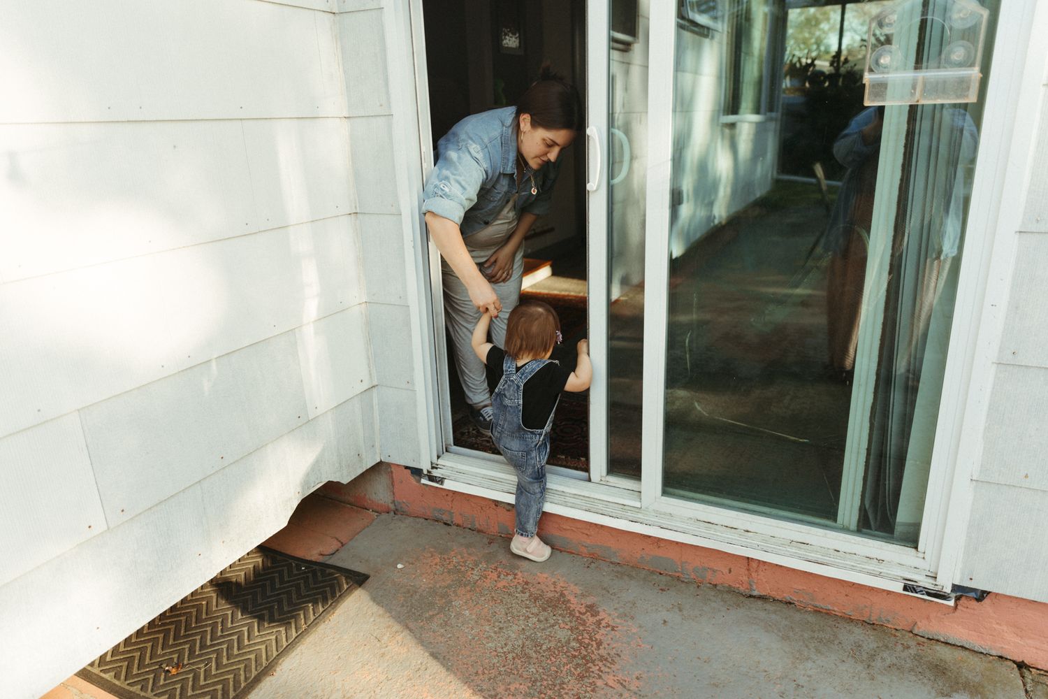 Someone crawls through a pet door entrance in a white wall.