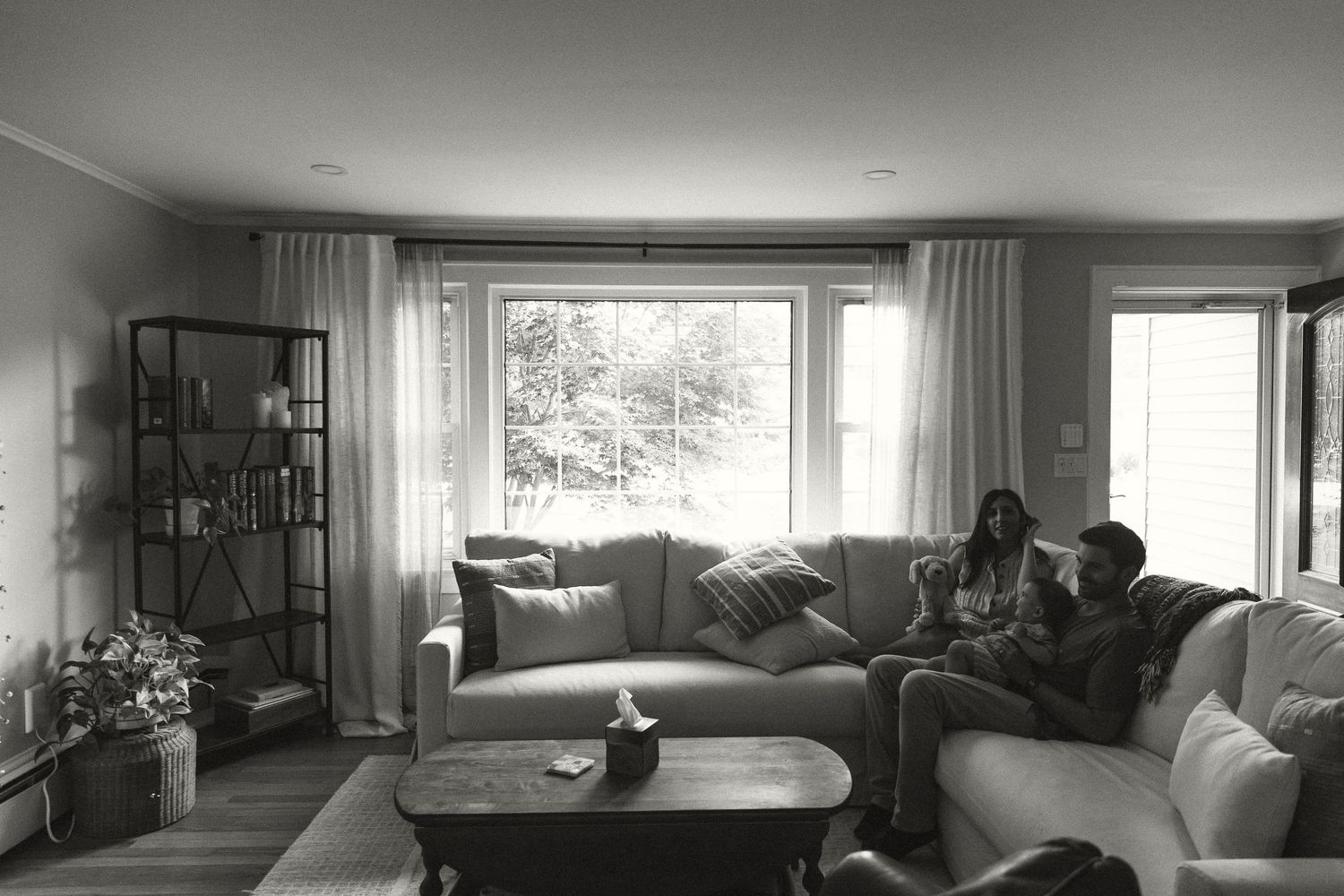 Panoramic view of modern living room interior with large windows and minimal furniture.