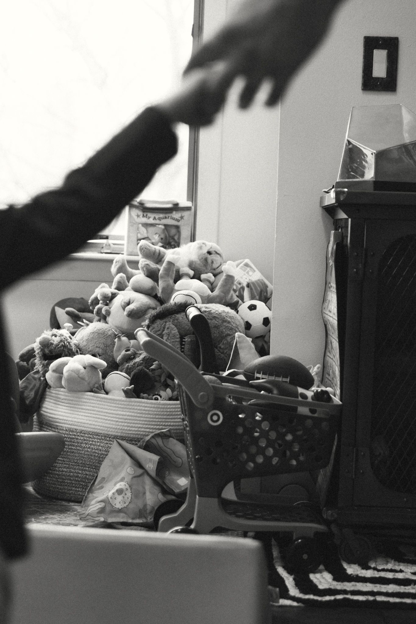 A black and white photo showing a collection of stuffed animals and toys piled in storage.