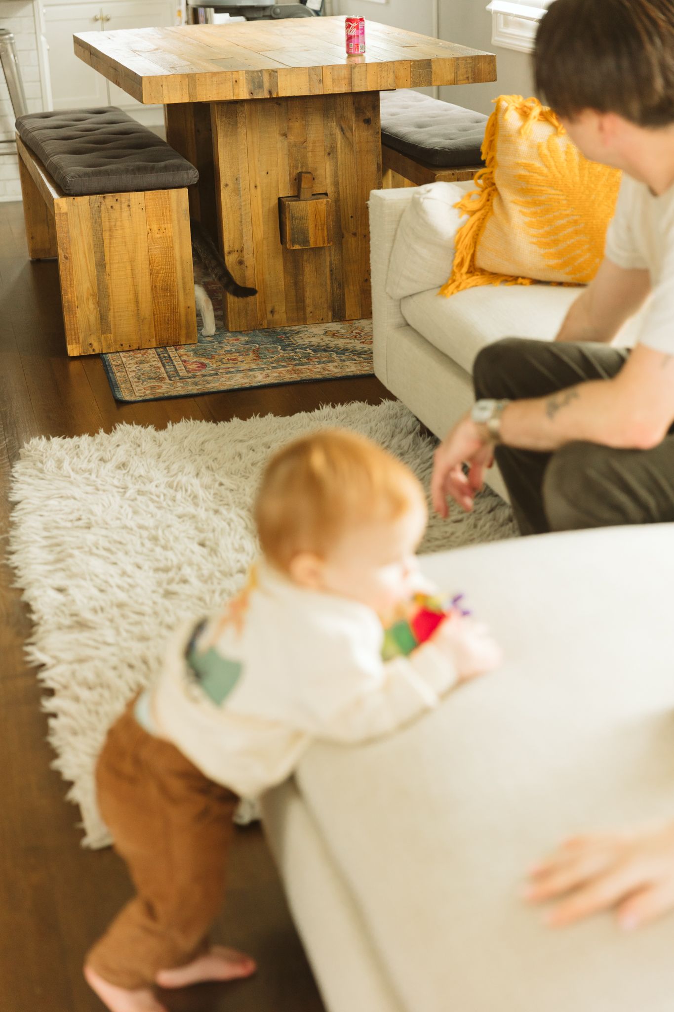 A rustic wooden coffee table with black bench seating on a white shag rug.