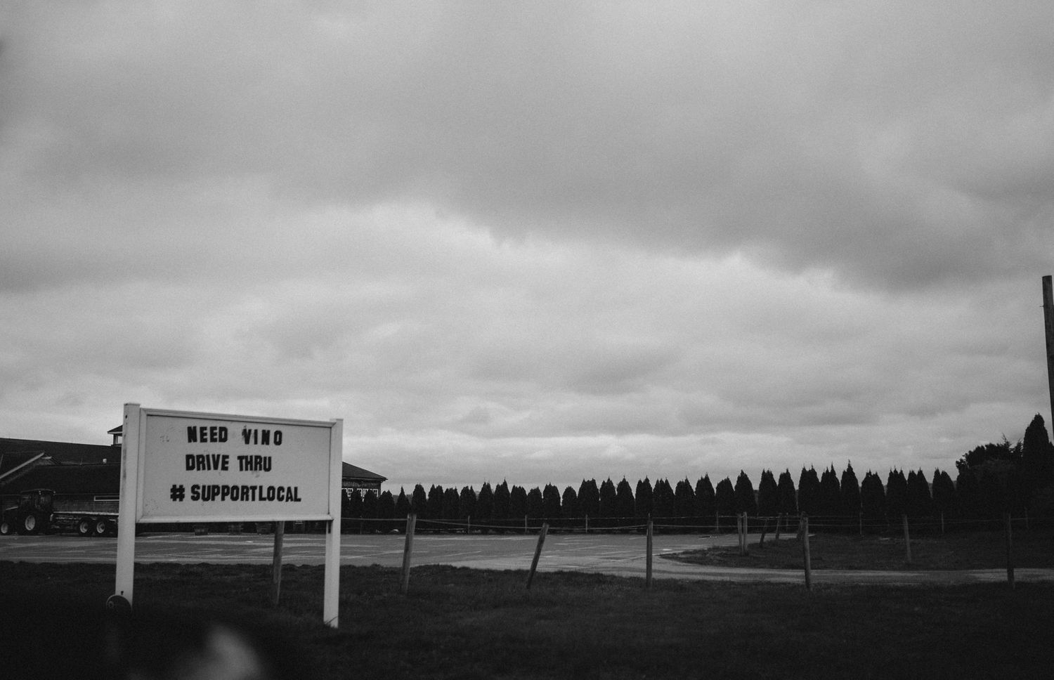 Black and white landscape with buildings visible on distant horizon under cloudy sky.