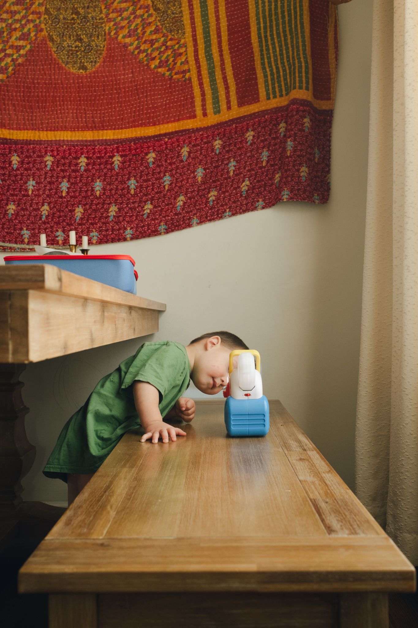 Four sequential images showing someone progressively reaching across a wooden table to grab a small blue object.