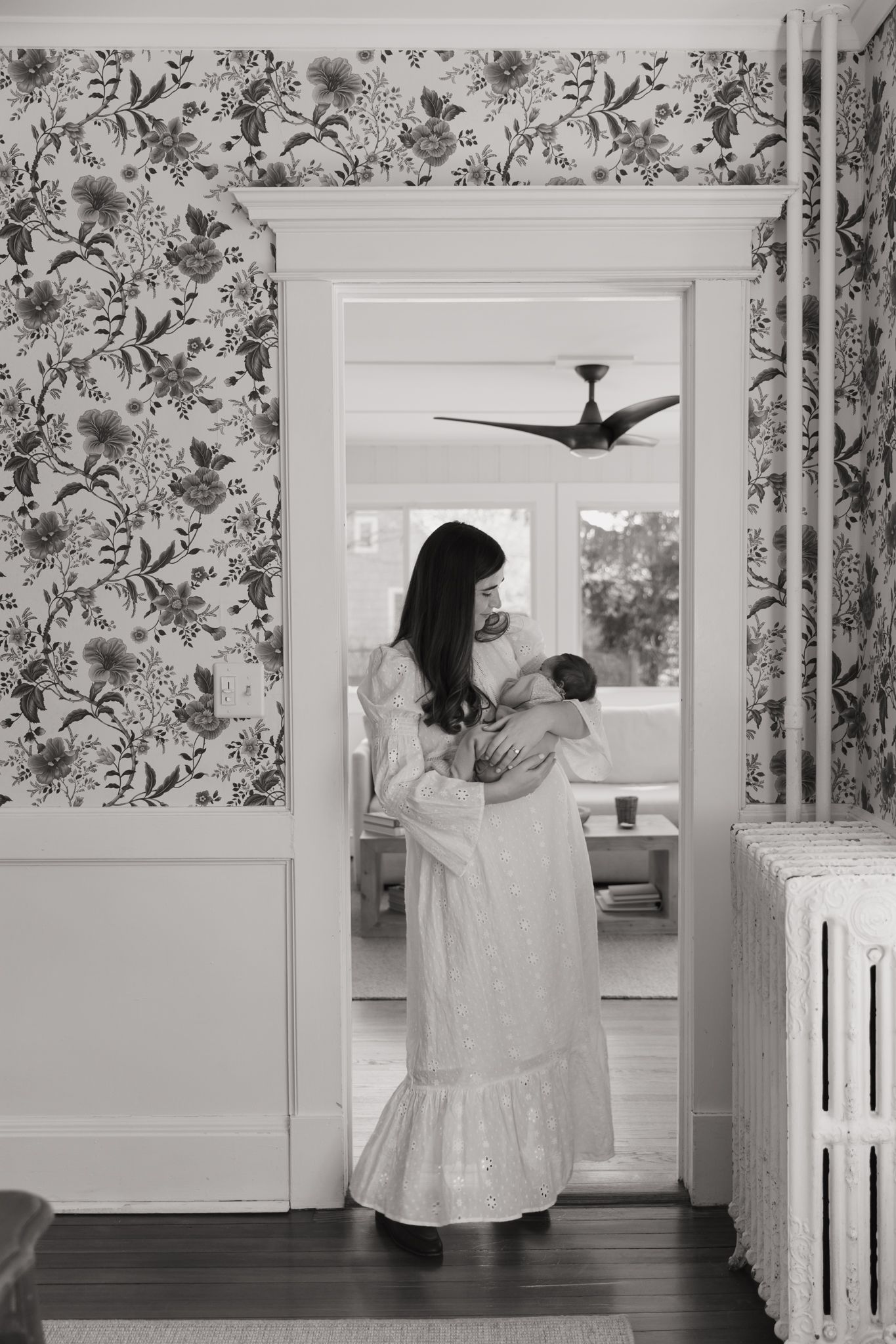 Black and white photos showing movement through a room with floral wallpaper and white doorframes.