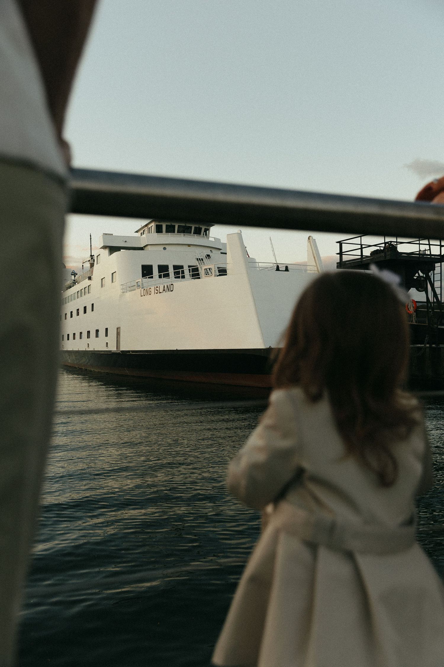A large white ferry boat docked at a pier viewed from a low angle.