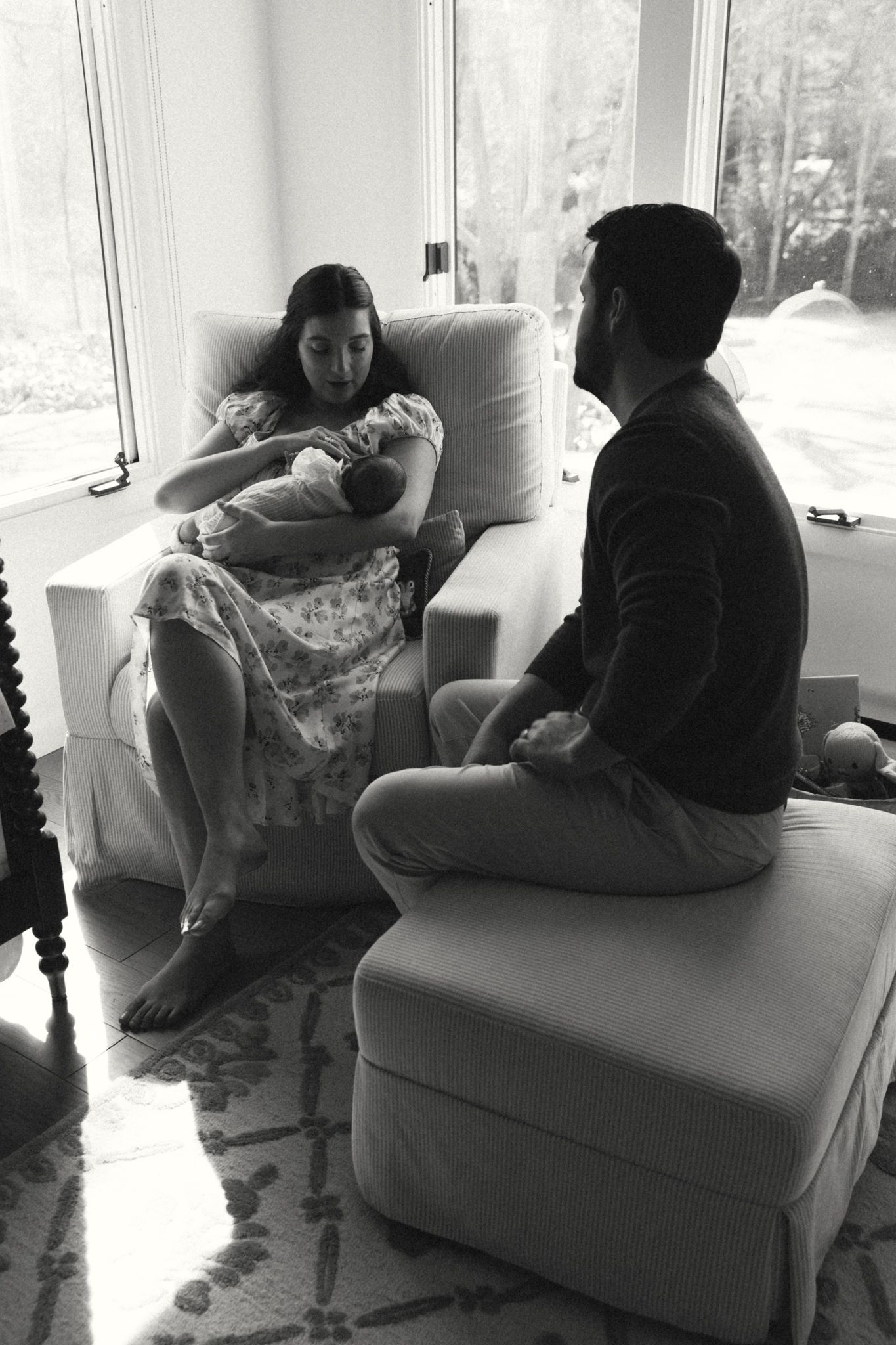 Family relaxing together on a white couch near bright windows.