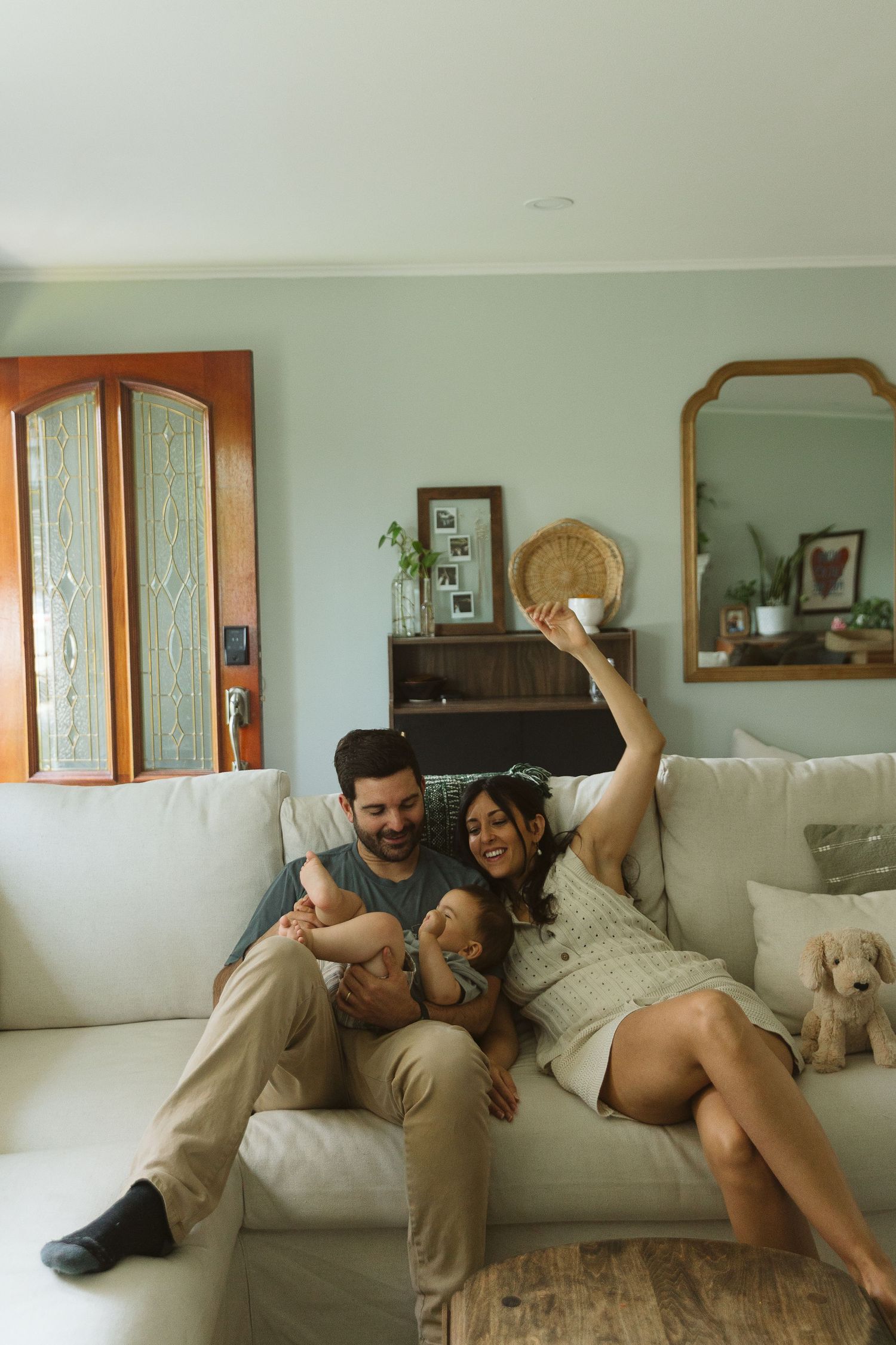 Family shares candid laughing moment on white couch in living room.
