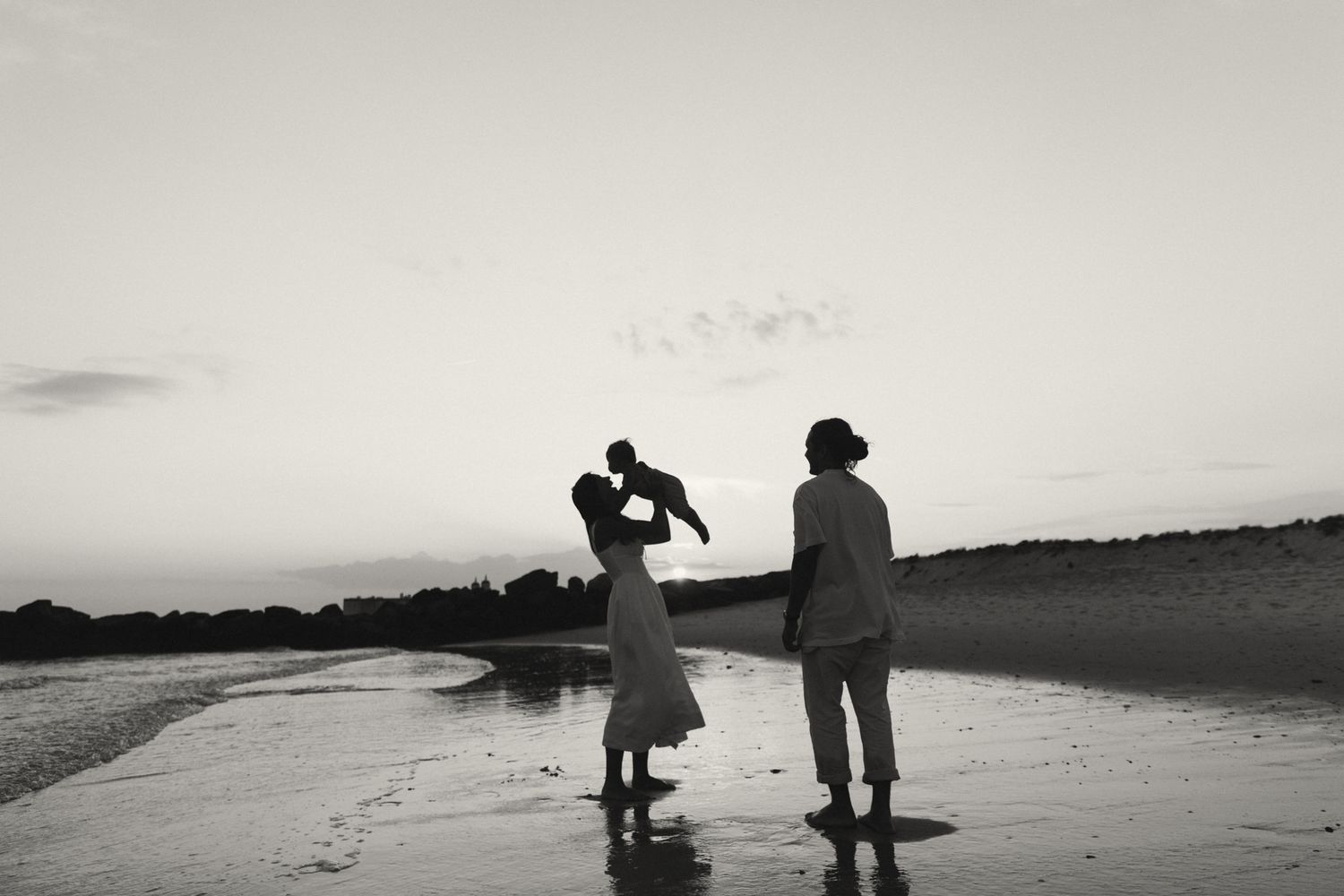 Silhouettes against a dramatic sunset sky on a beach landscape.