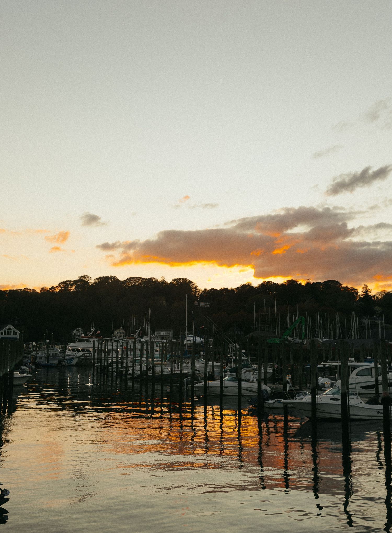 Marina at sunset with silhouetted boats and docks against an orange sky.