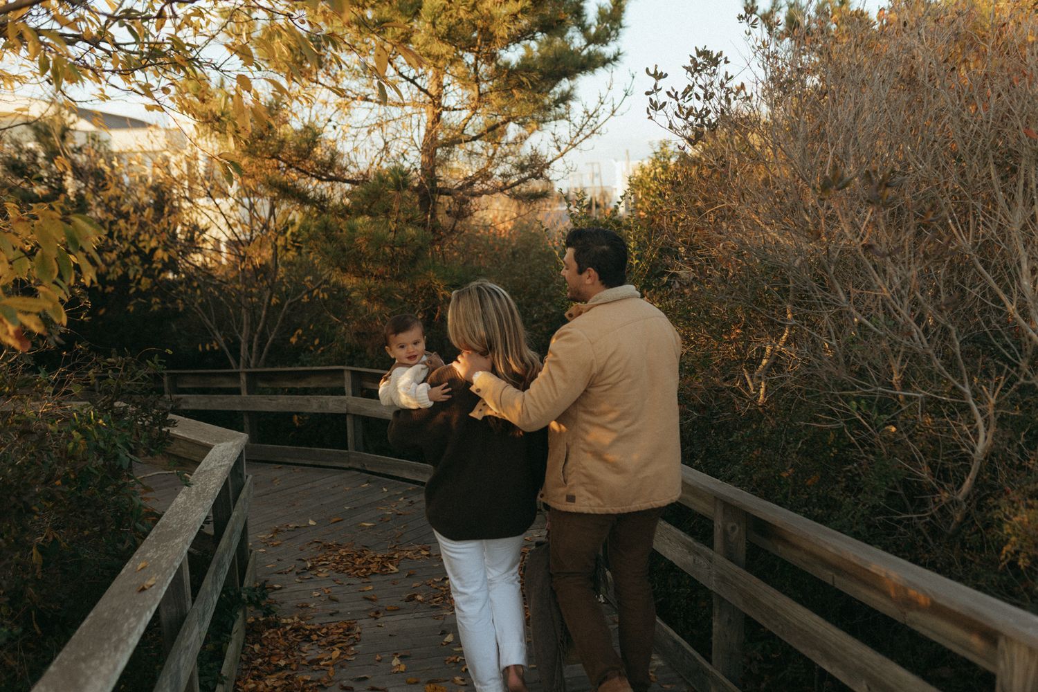 Autumn scene on a wooden boardwalk surrounded by fall foliage at sunset.