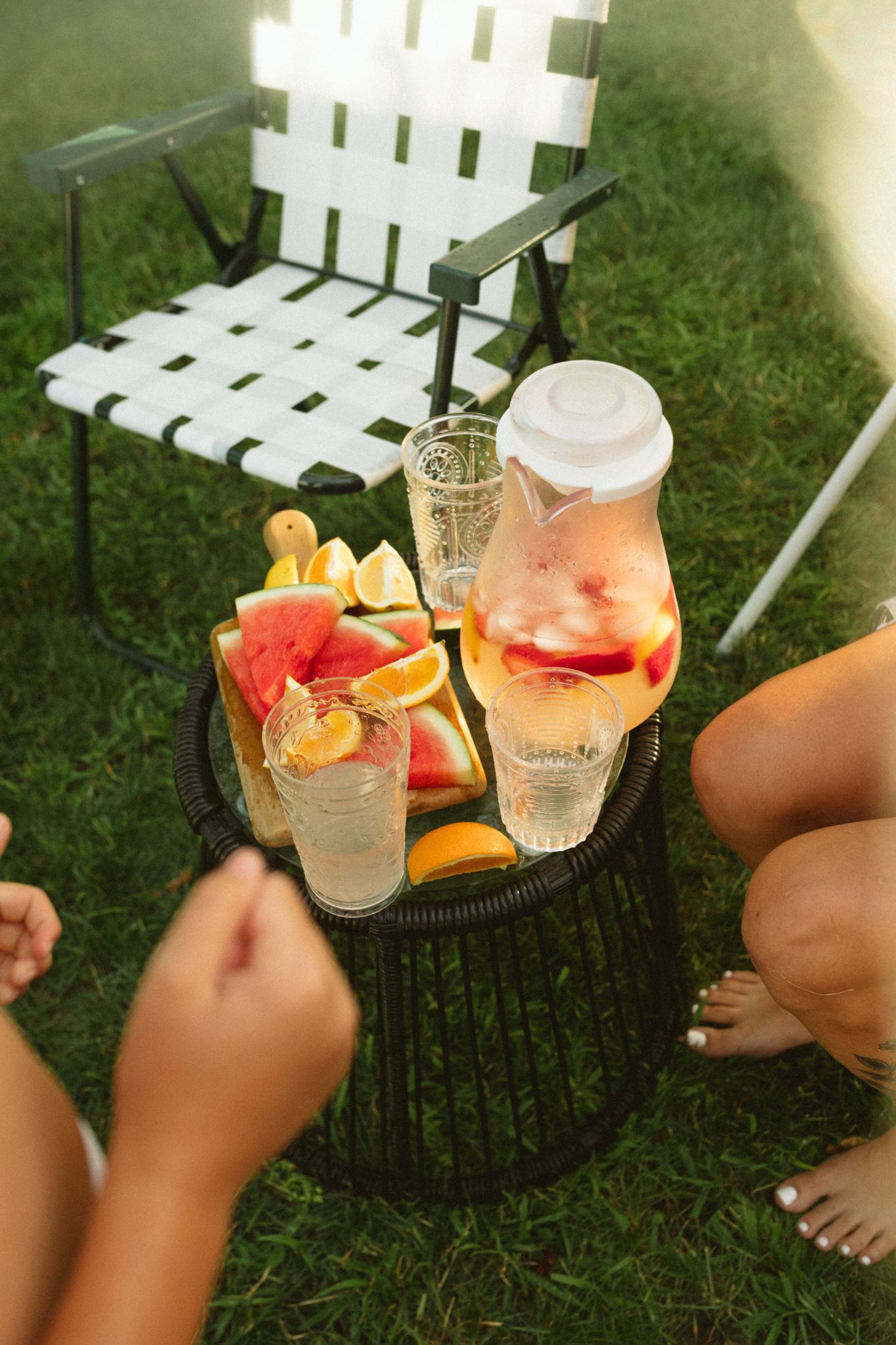 Refreshing summer drinks with citrus garnishes on a white outdoor bench.