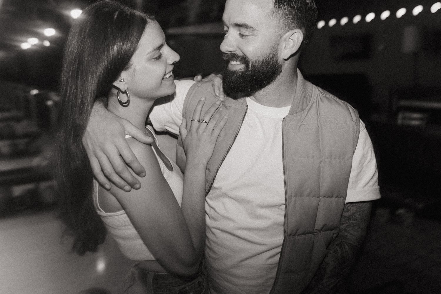 Black and white photos showing a couple sharing intimate moments under string lights.