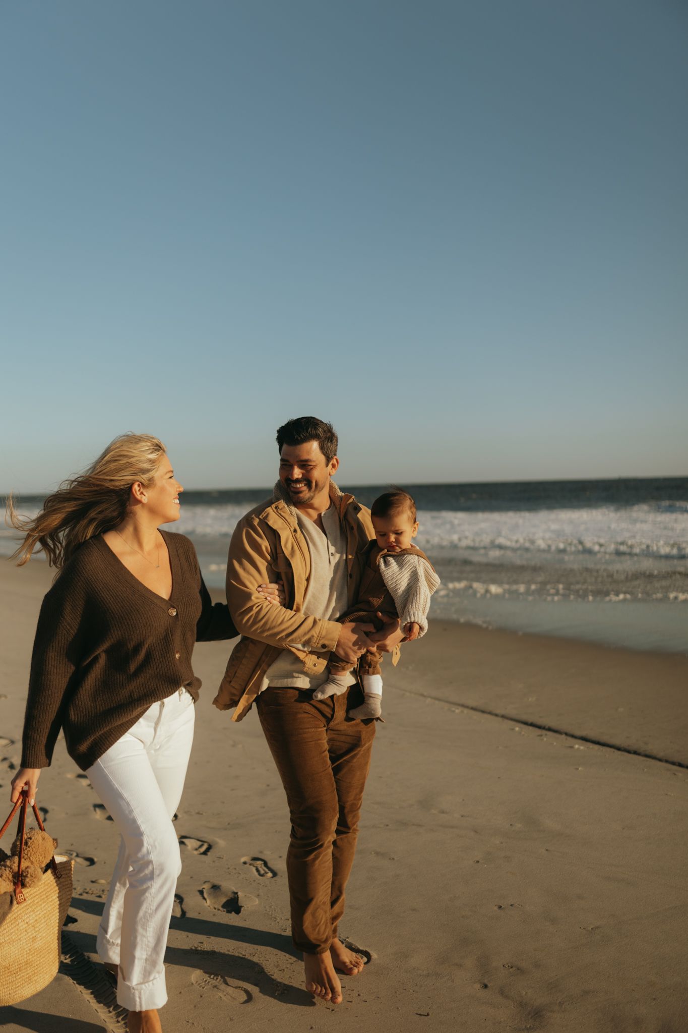 A family takes a leisurely stroll along the shoreline on a sunny beach day.