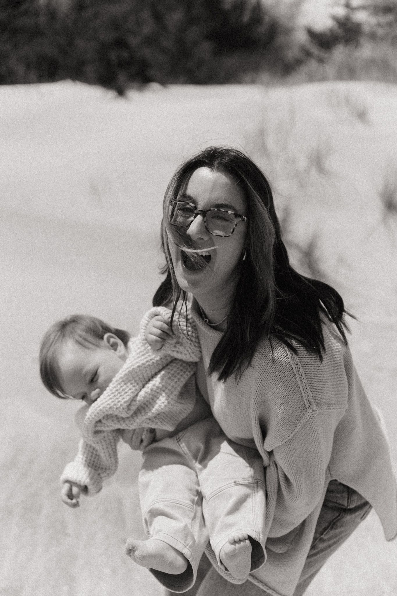 Black and white photos capturing intimate family moments on a sandy beach.
