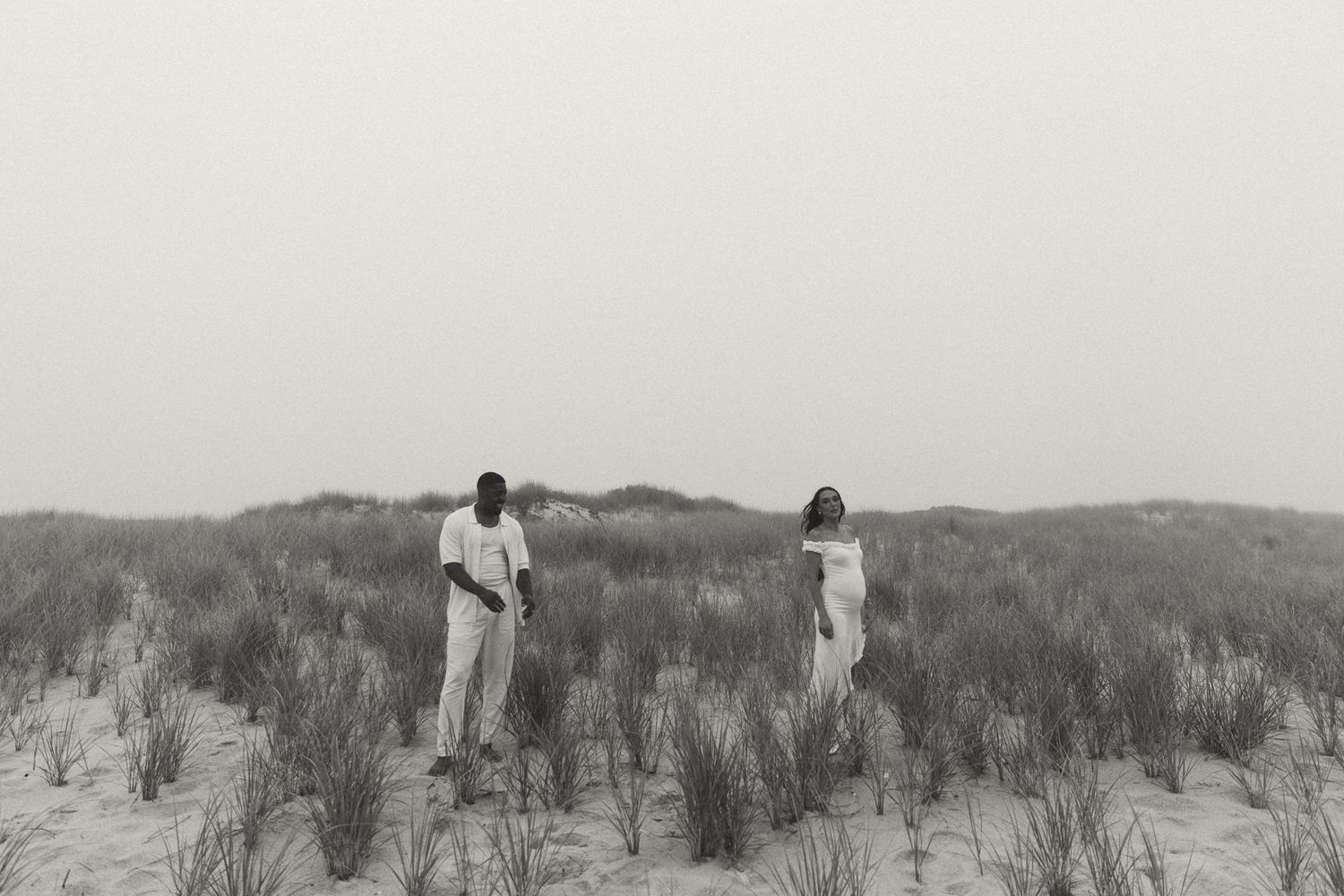 Distant figures walking through coastal dunes in ethereal light.
