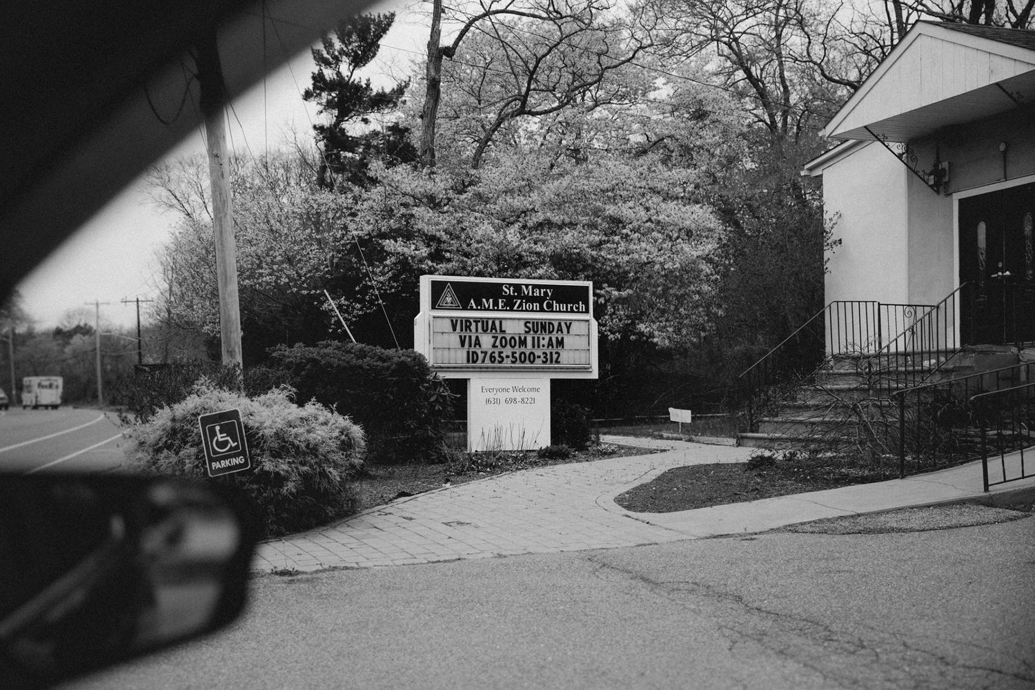 A church sign photographed through a car window in black and white.