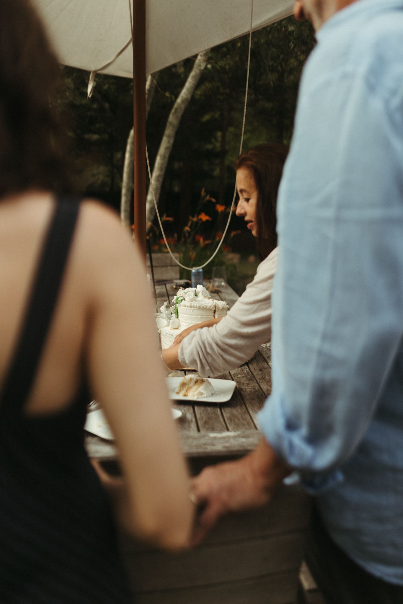 People enjoying a casual outdoor gathering at a rustic wooden table.