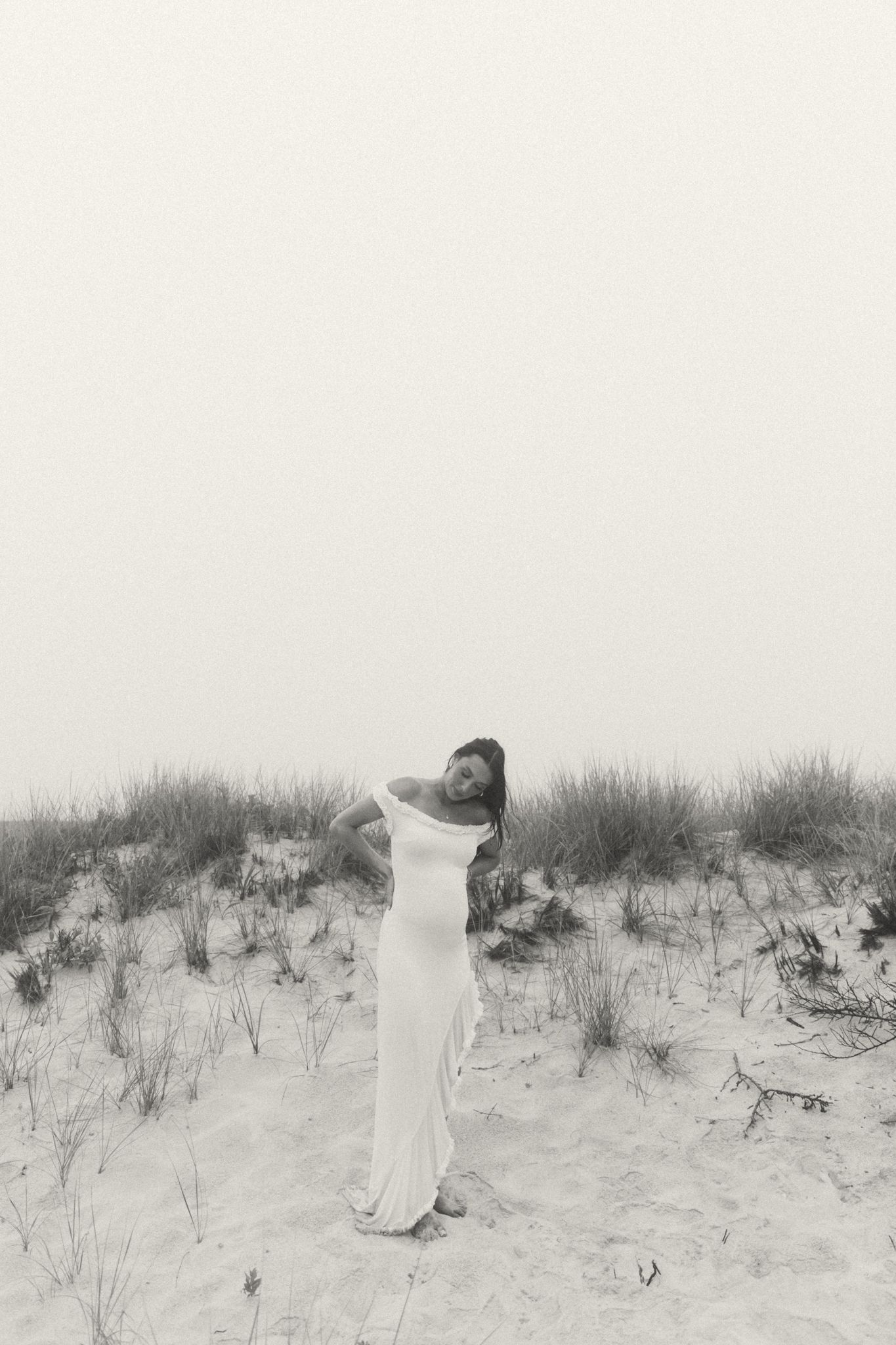 Artistic black and white photo of figures moving through beach grass landscape.