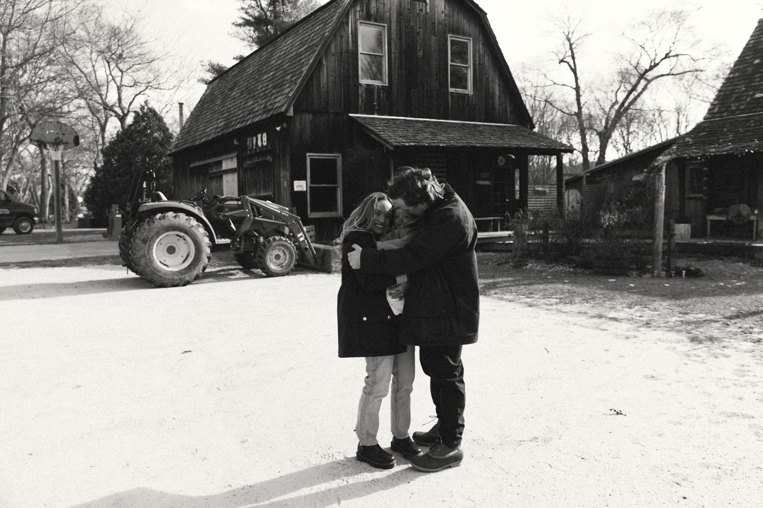 Black and white photo of a farm scene with a barn and tractor in the background.