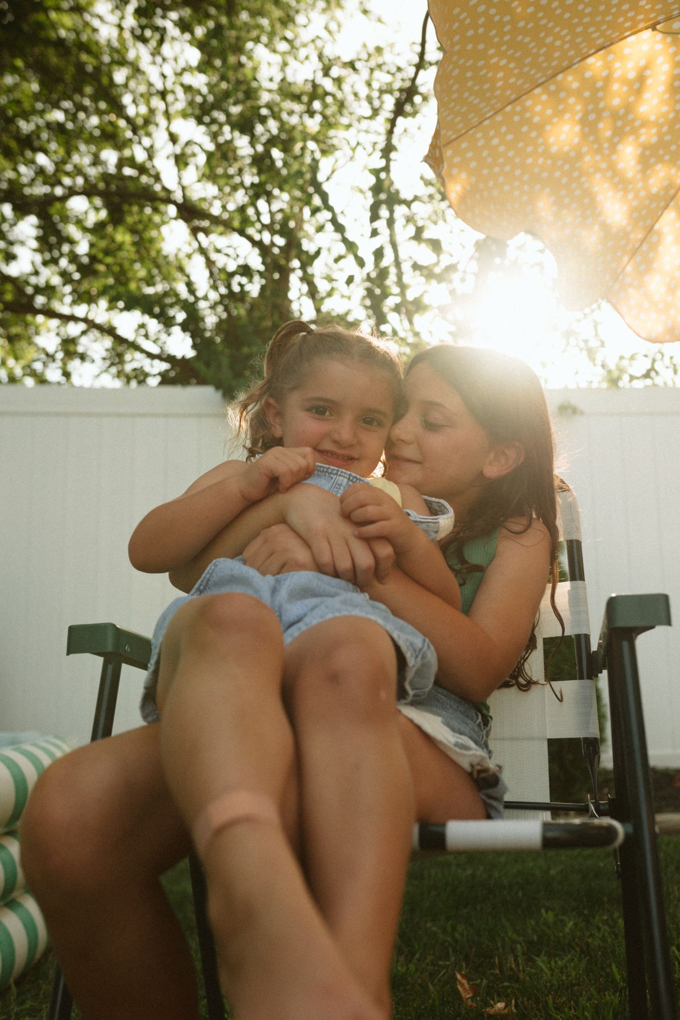 Sun-drenched backyard scene with two figures relaxing on a lounge chair.